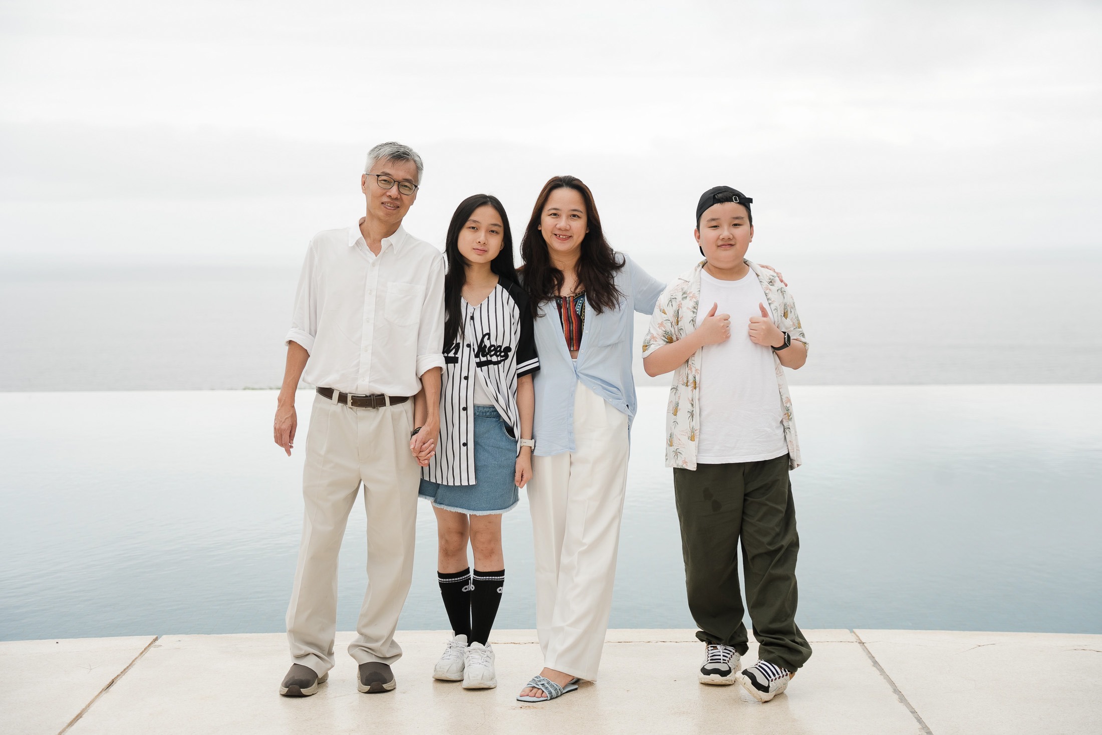 Family portrait near infinity edge pool at Alila Villas Uluwatu Bali with calm ocean backdrop