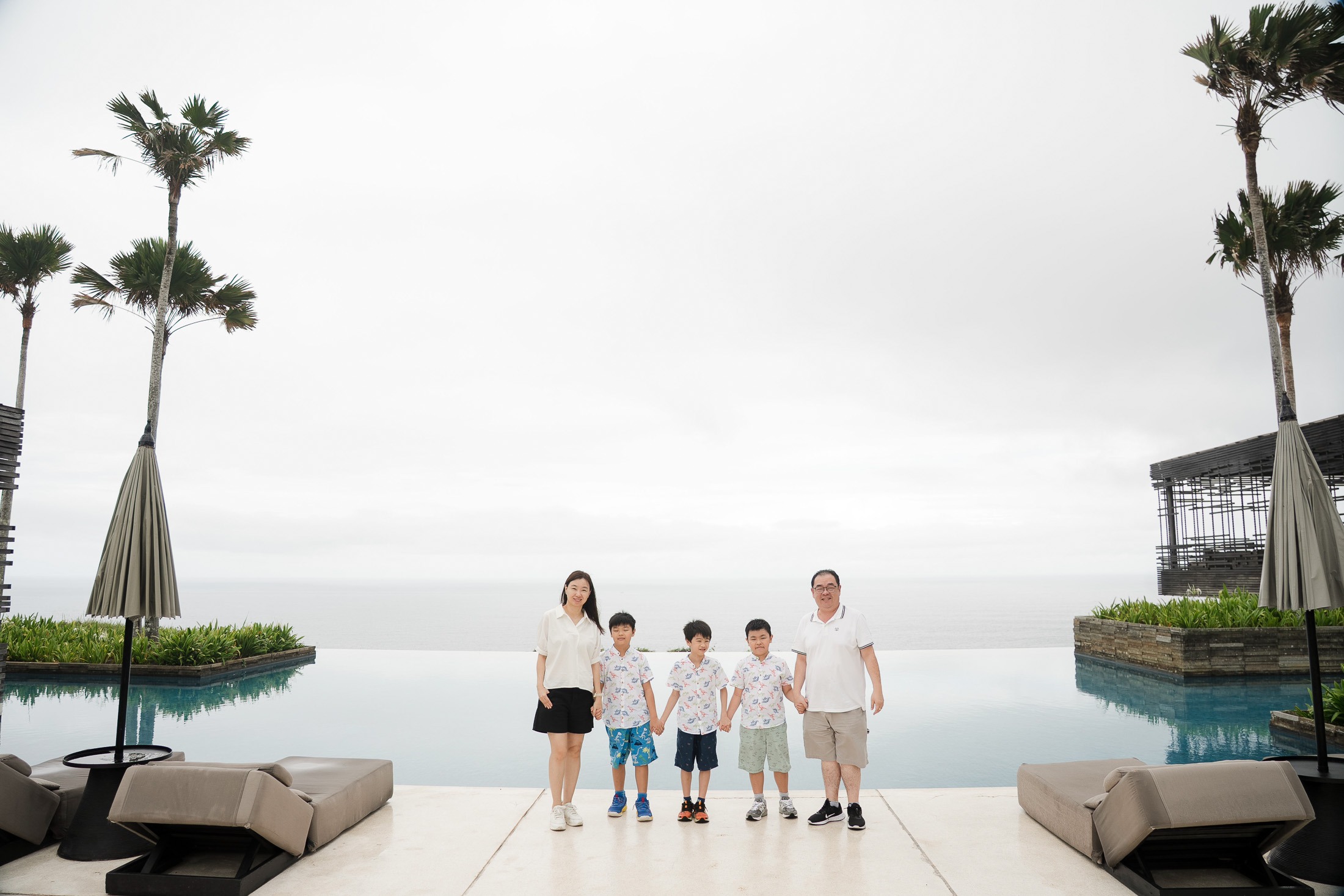 Extended family wide shot at Alila Villas Uluwatu Bali with ocean horizon and architectural symmetry