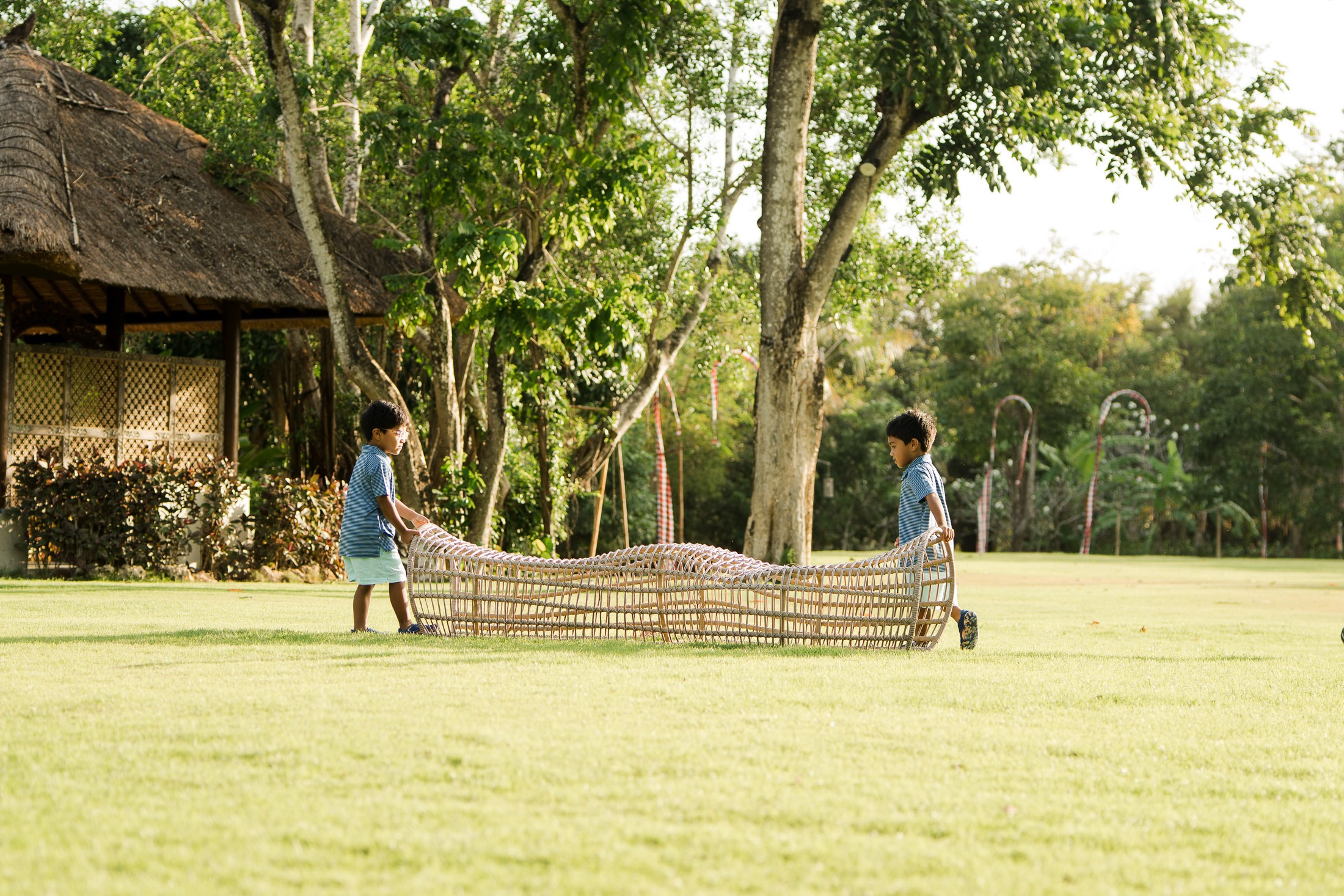 mother kneeling and embracing her children on the lawn at rimba by ayana bali during natural bali family photography