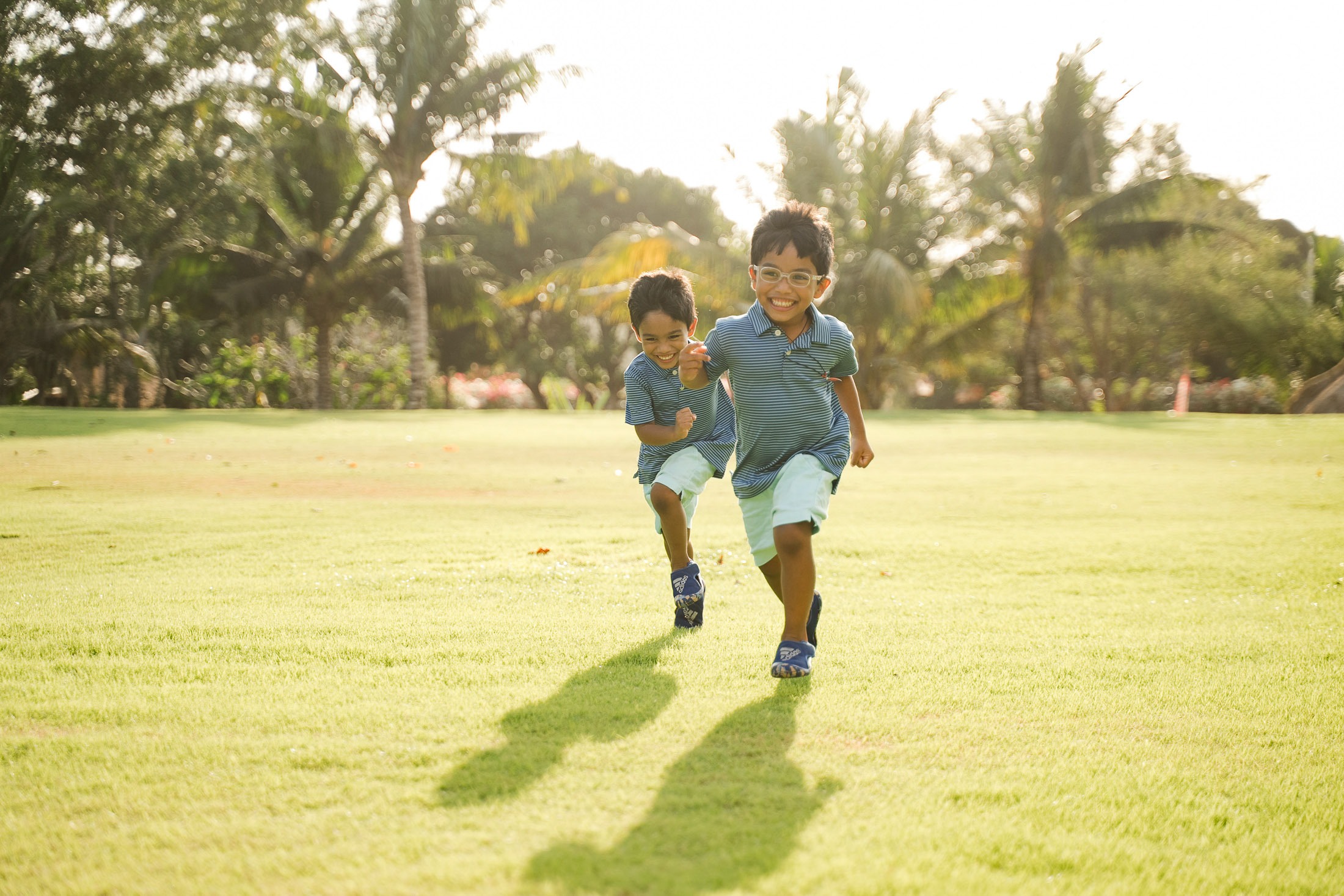 two children running and playing on the lawn at rimba by ayana bali during a bali family photography session
