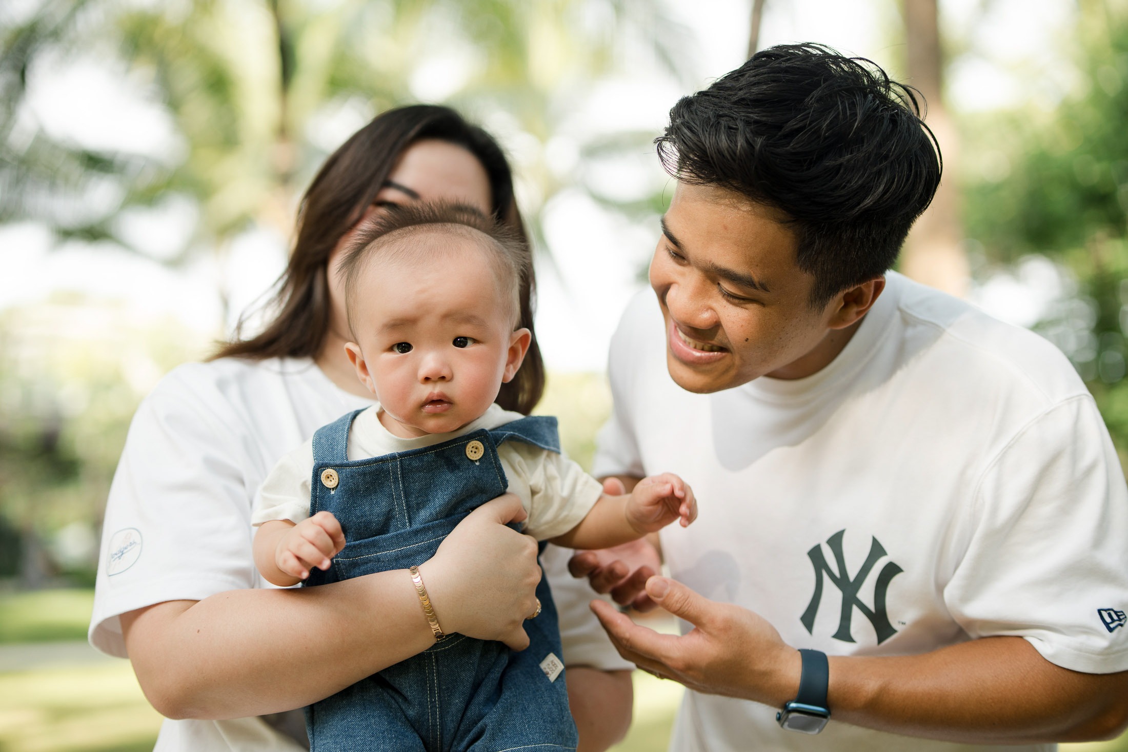 Parents holding their baby during a relaxed family photography session at The Apurva Kempinski Nusa Dua Bali