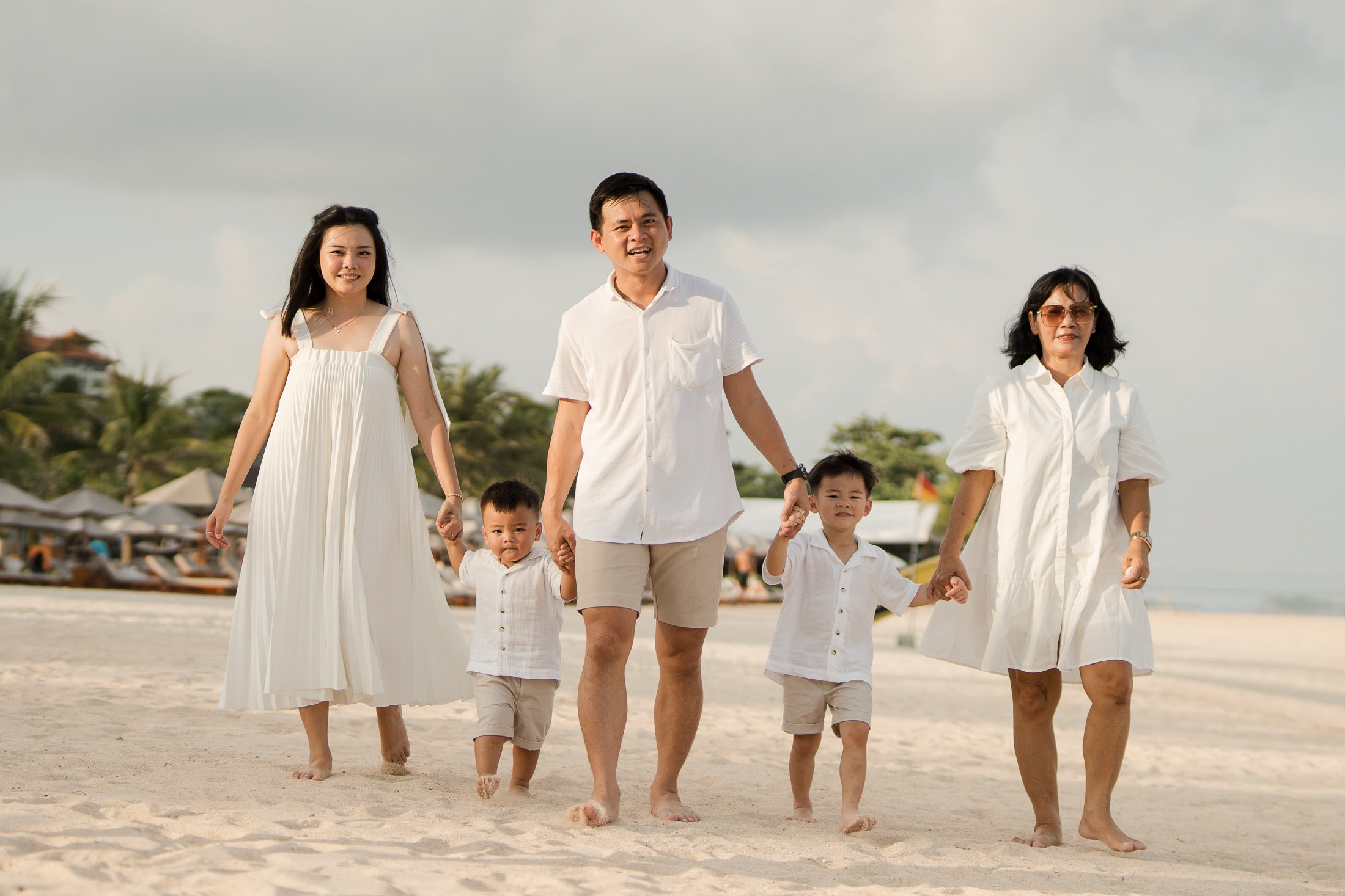Parents walking with their children along the beach at The Apurva Kempinski Nusa Dua Bali