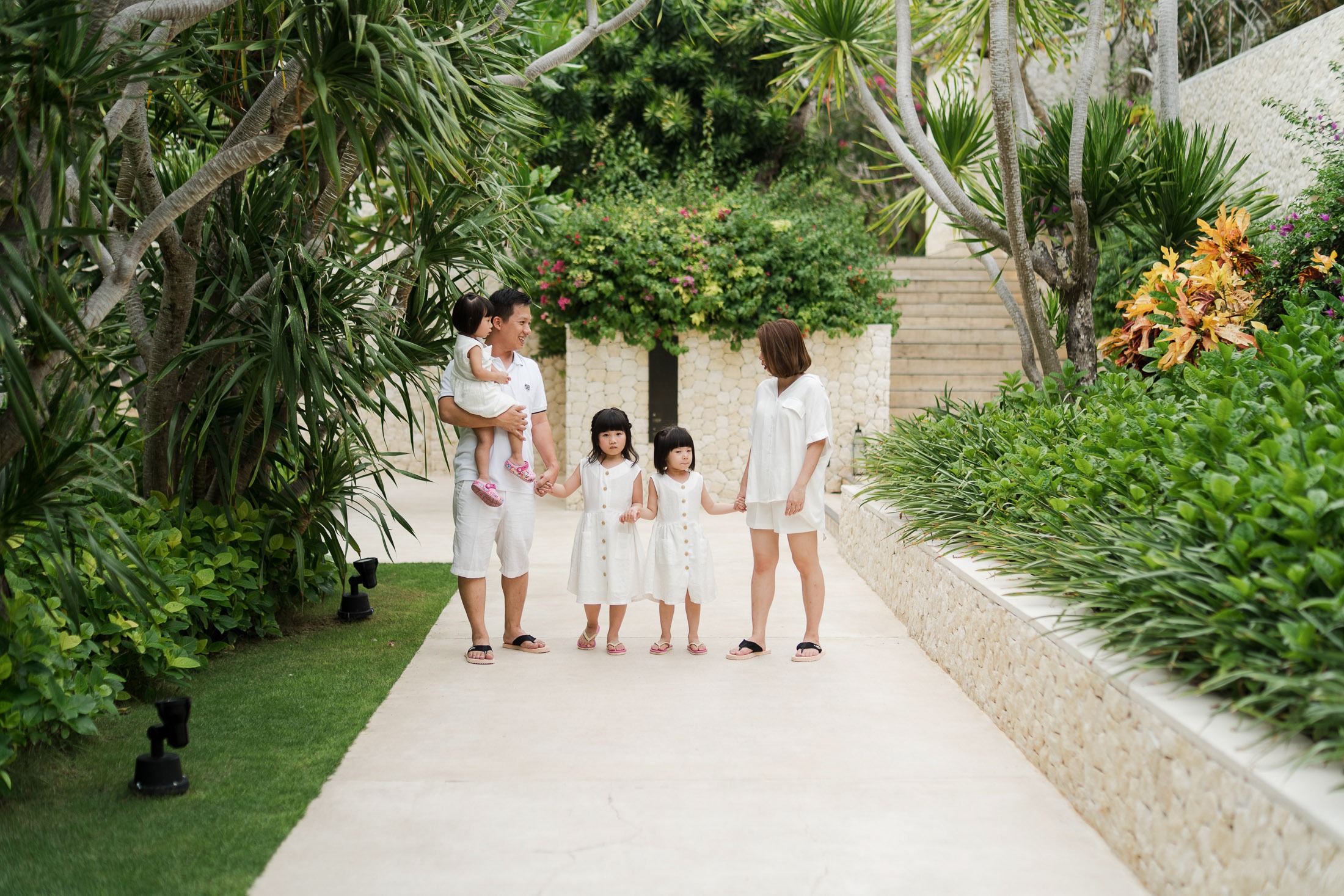 Natalia family walking through tropical garden pathway at The Mulia Nusa Dua Bali during a family photo session