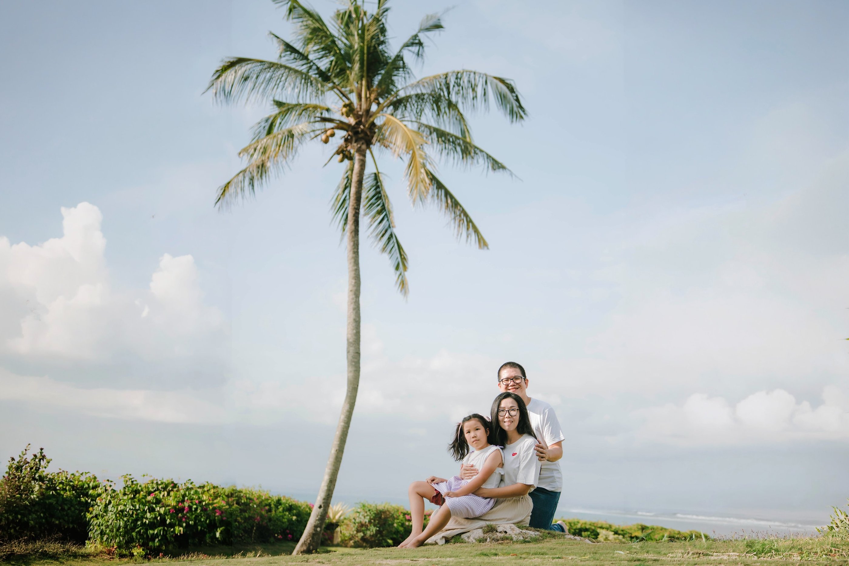 Family portrait at AYANA Villas Jimbaran Bali with ocean view and palm trees – luxury family photography in Bali