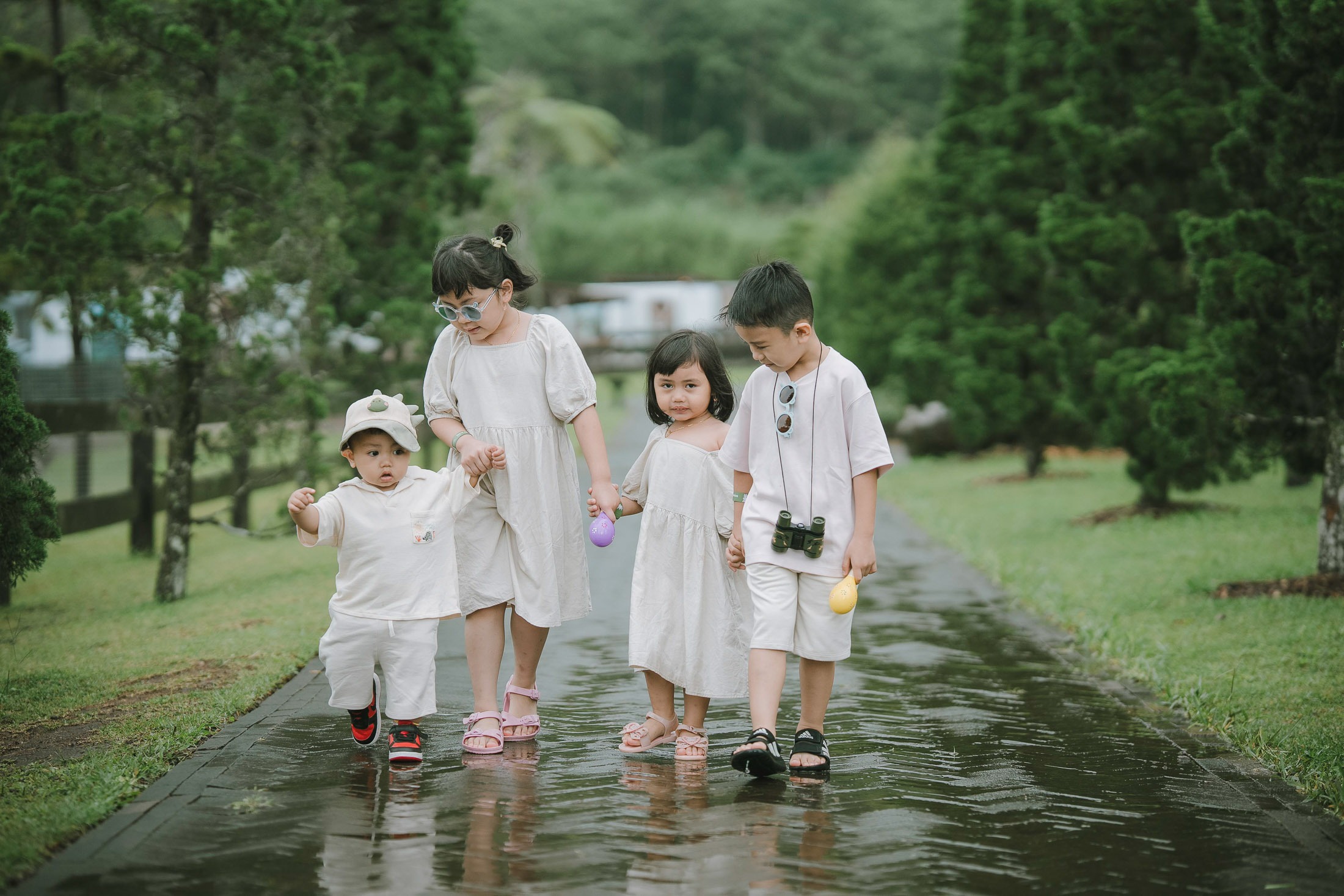 Family walking on wet garden path during a family photography session at Bali Farm House Bedugul Bali.
