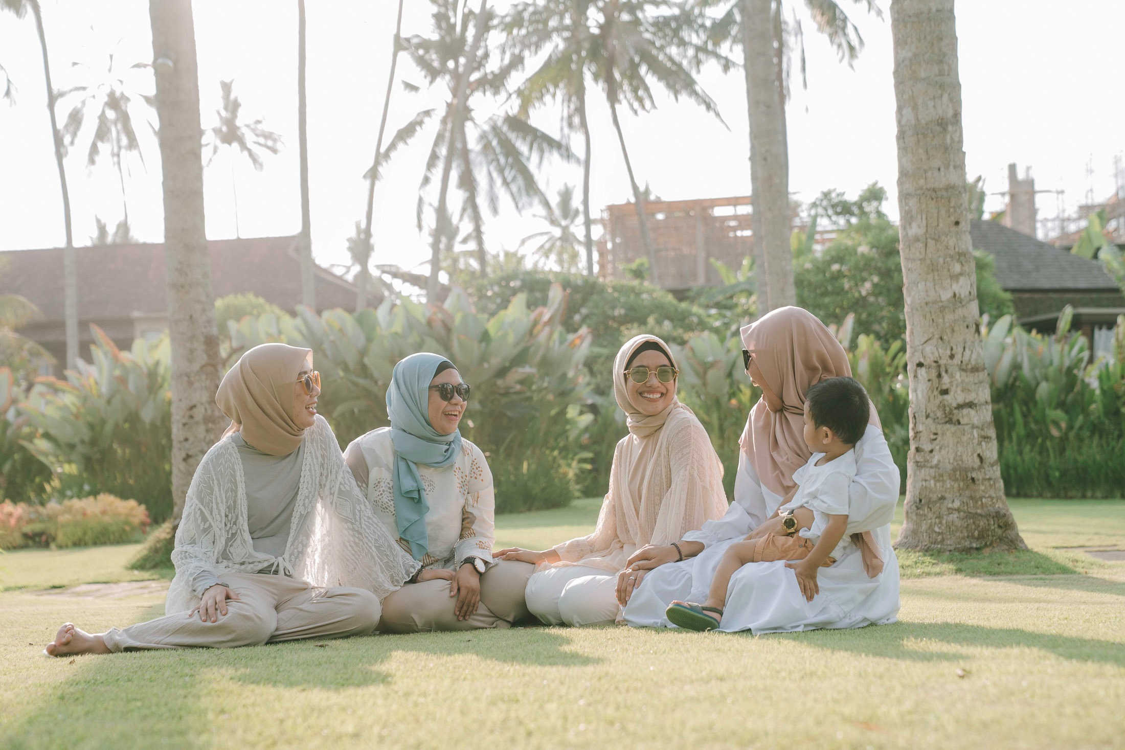 Friends sitting and talking on lawn during photoshoot at Candi Beach Resort Karangasem Bali