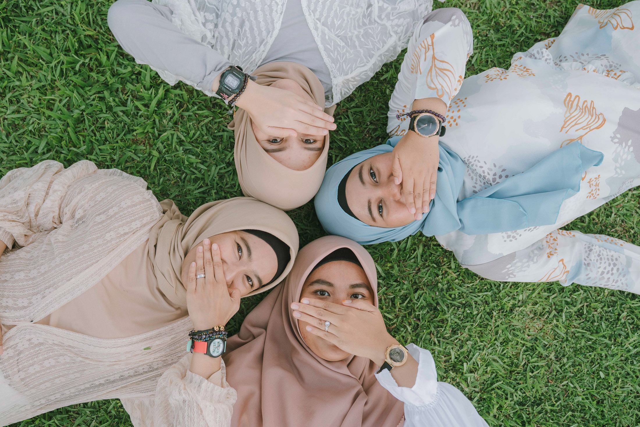 Friends lying together on grass during lifestyle photoshoot at Candi Beach Resort Karangasem Bali