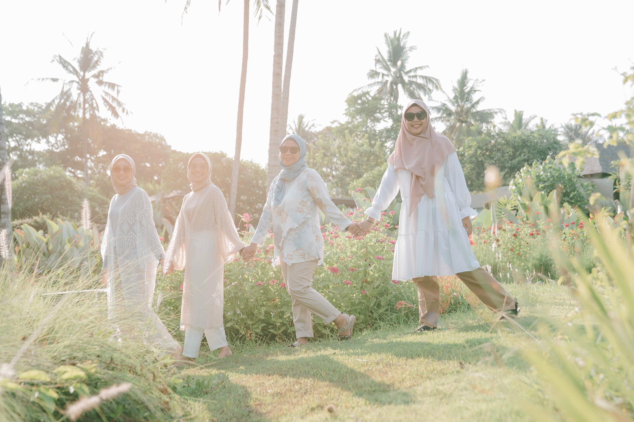 Friends walking together through garden during sunset photoshoot at Candi Beach Resort Karangasem Bali