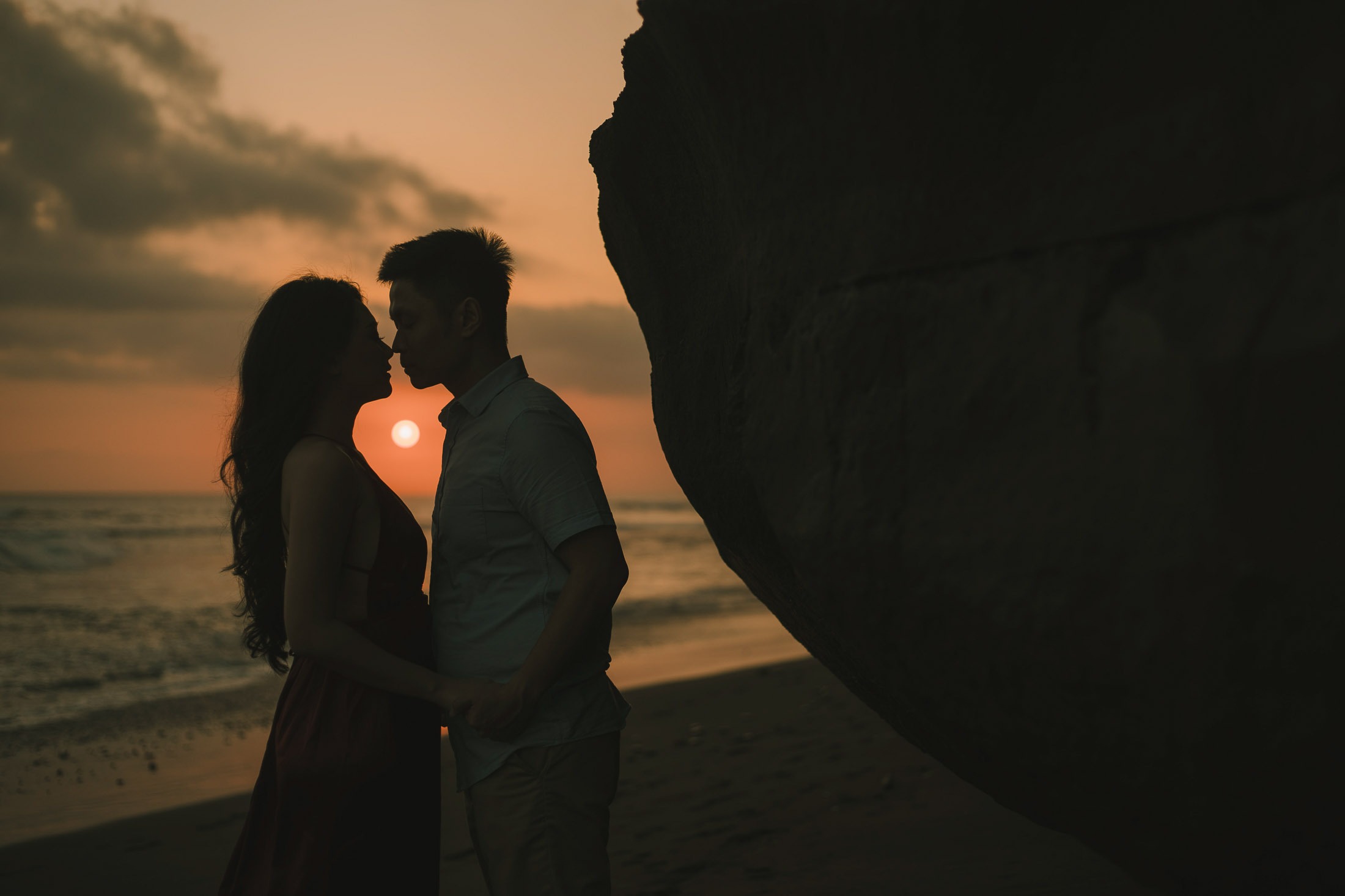 Silhouette of intimate couple kissing during sunset at Pantai Nyanyi Bali.