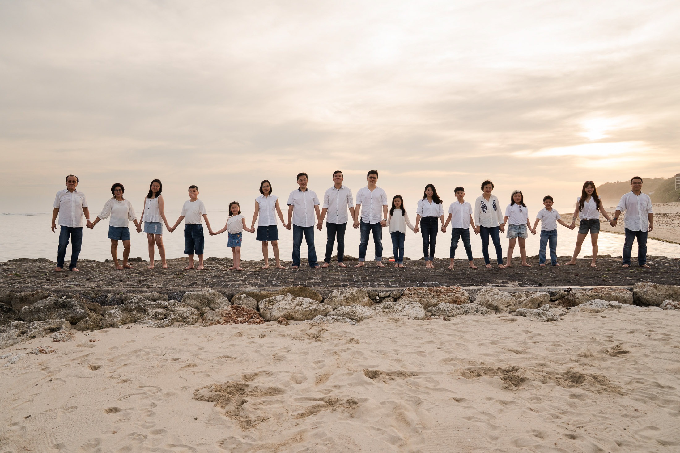 Large family standing together in a line on the beach during sunset at The Ritz-Carlton Bali Nusa Dua
