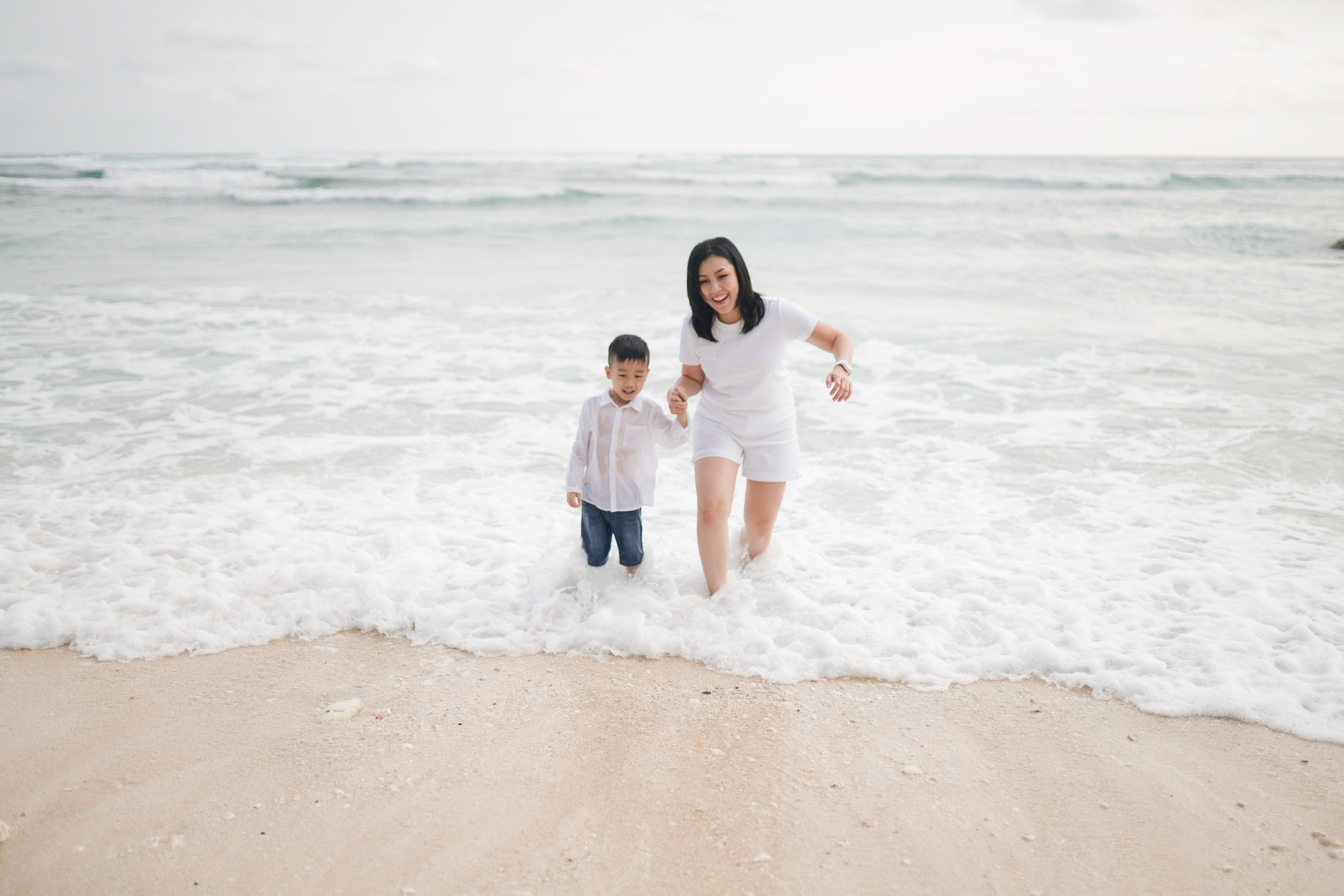 Parents and child standing near the shoreline of Melasti Beach Bali during a natural family photography session