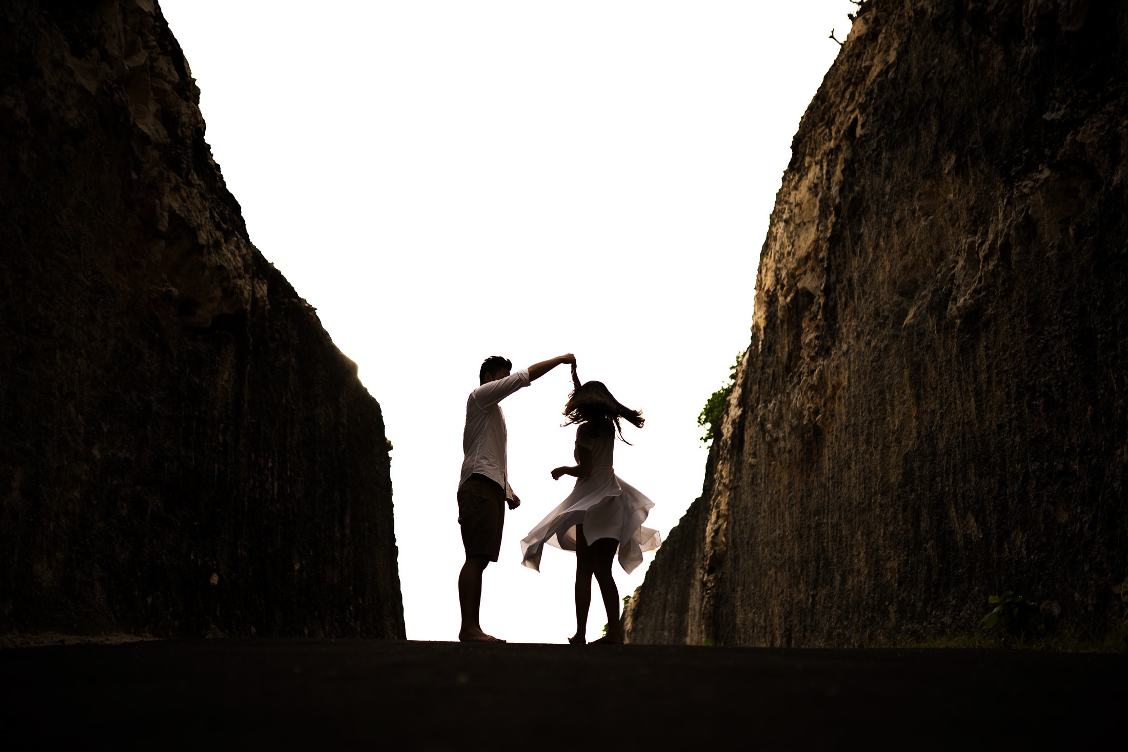 Silhouette couple proposal between cliffs at Melasti Beach Bali during sunset