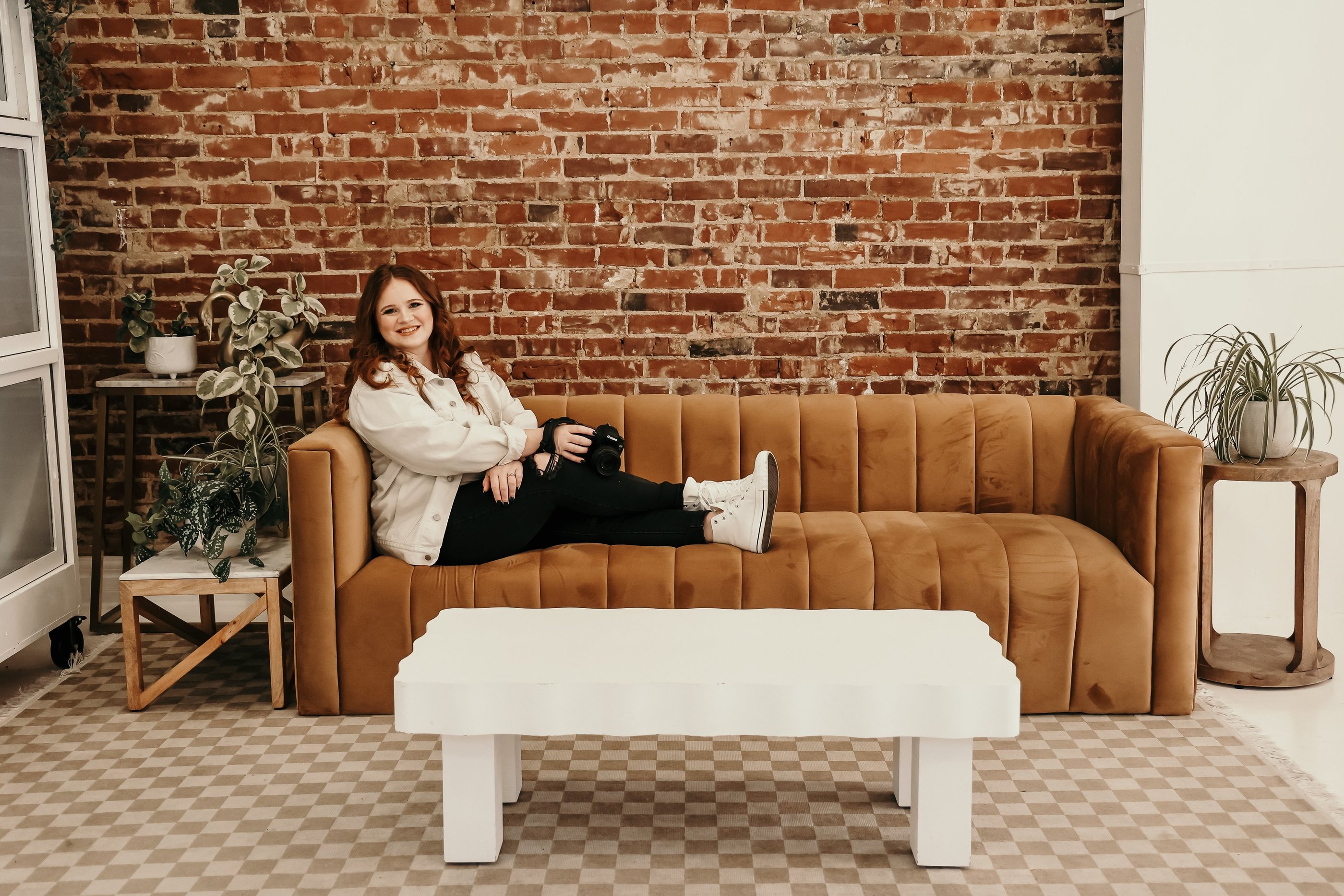 Rachel sits on a couch smiling at the camera