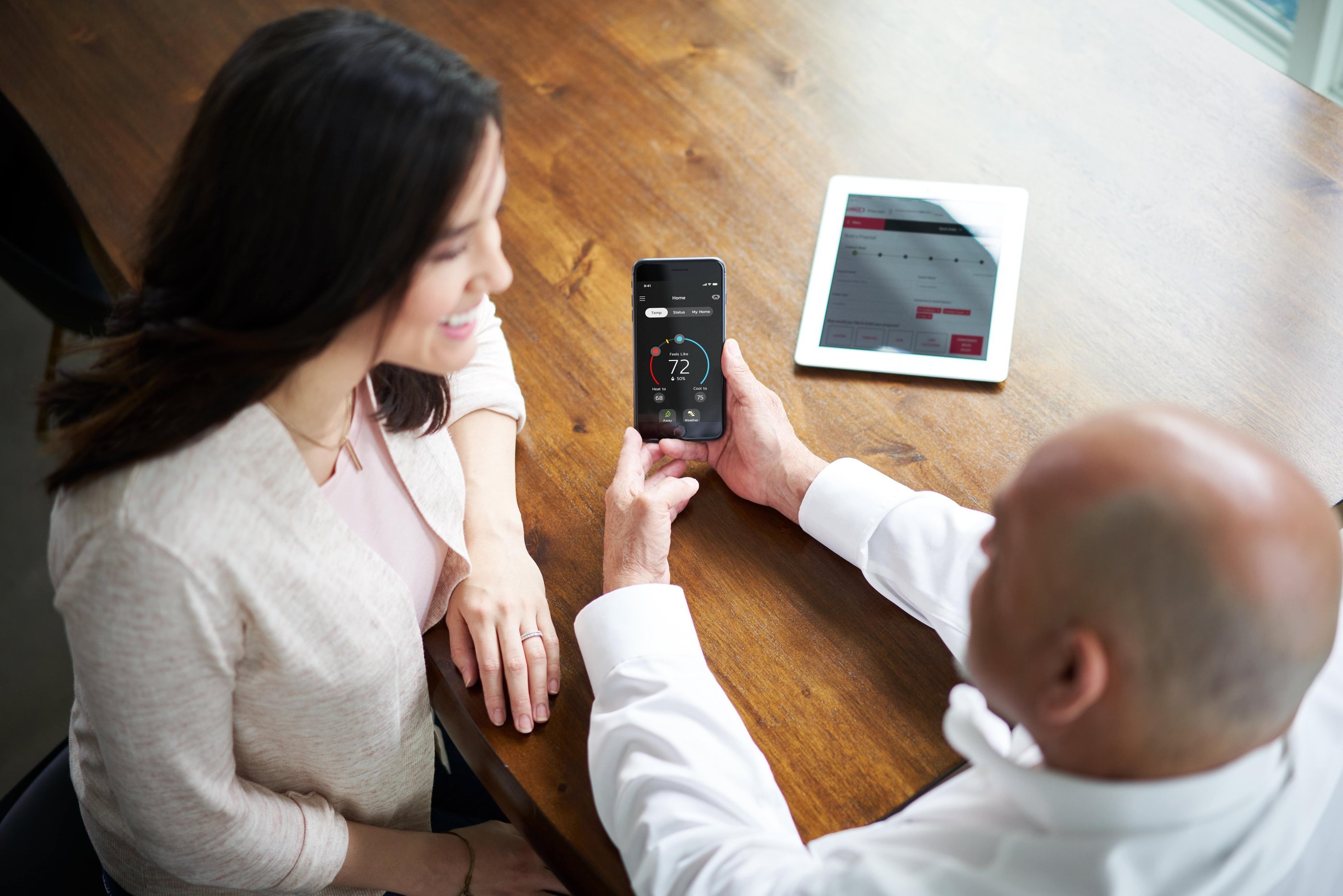 a man and woman sitting at a table with a tablet