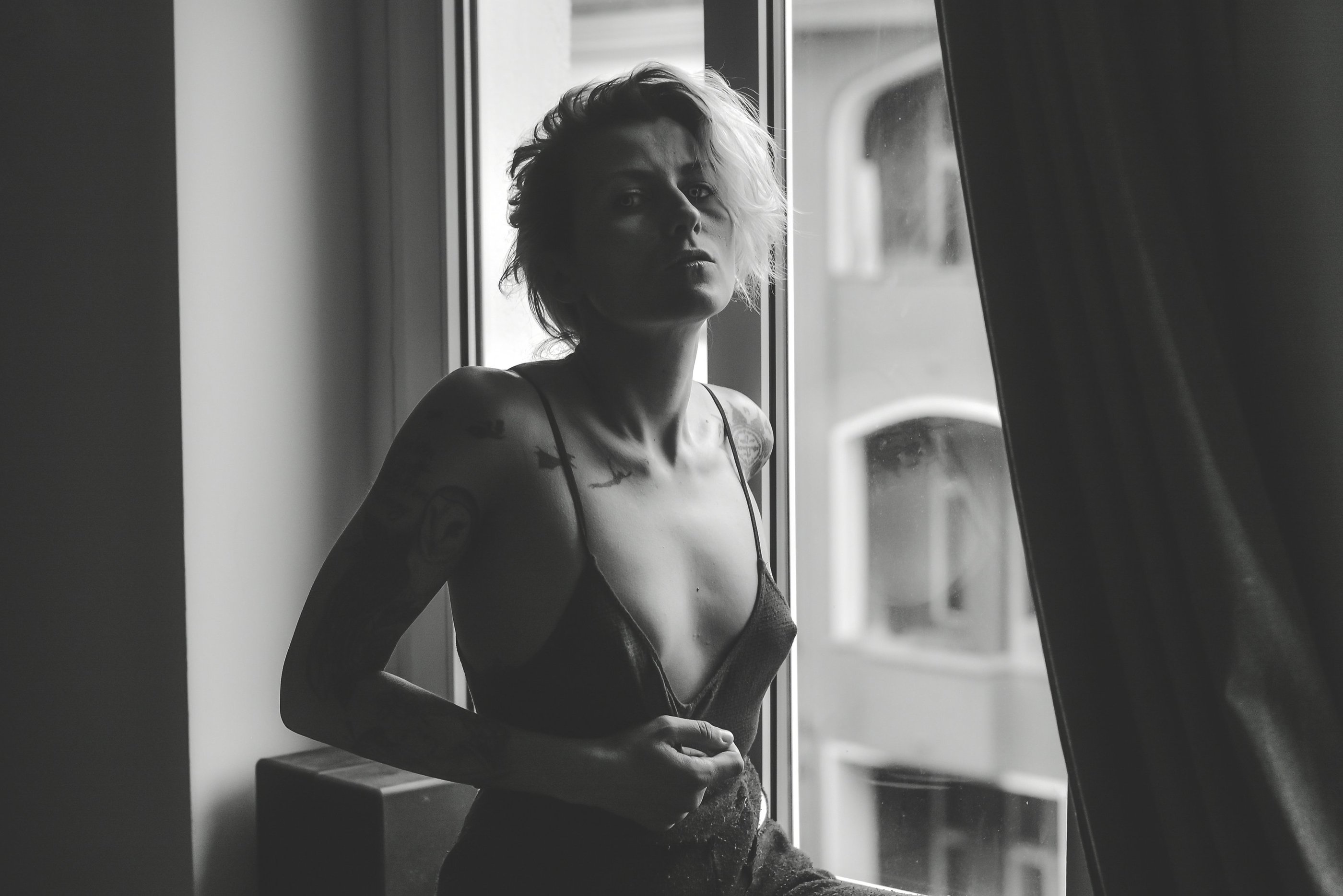 a woman in a lingersuit sitting on a window sill posing for a photo