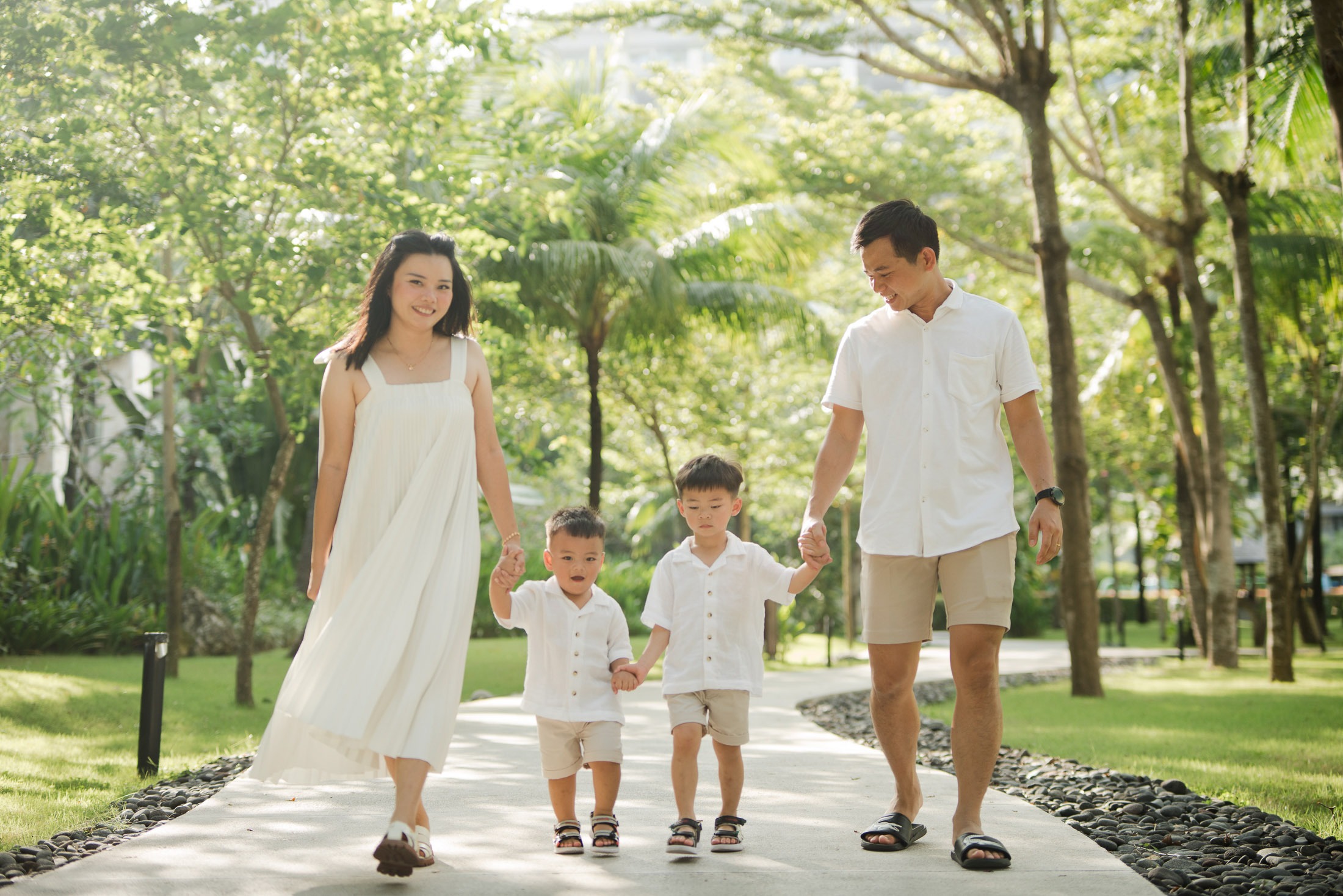 Parents walking with their children through tropical garden pathways at The Apurva Kempinski Nusa Dua Bali