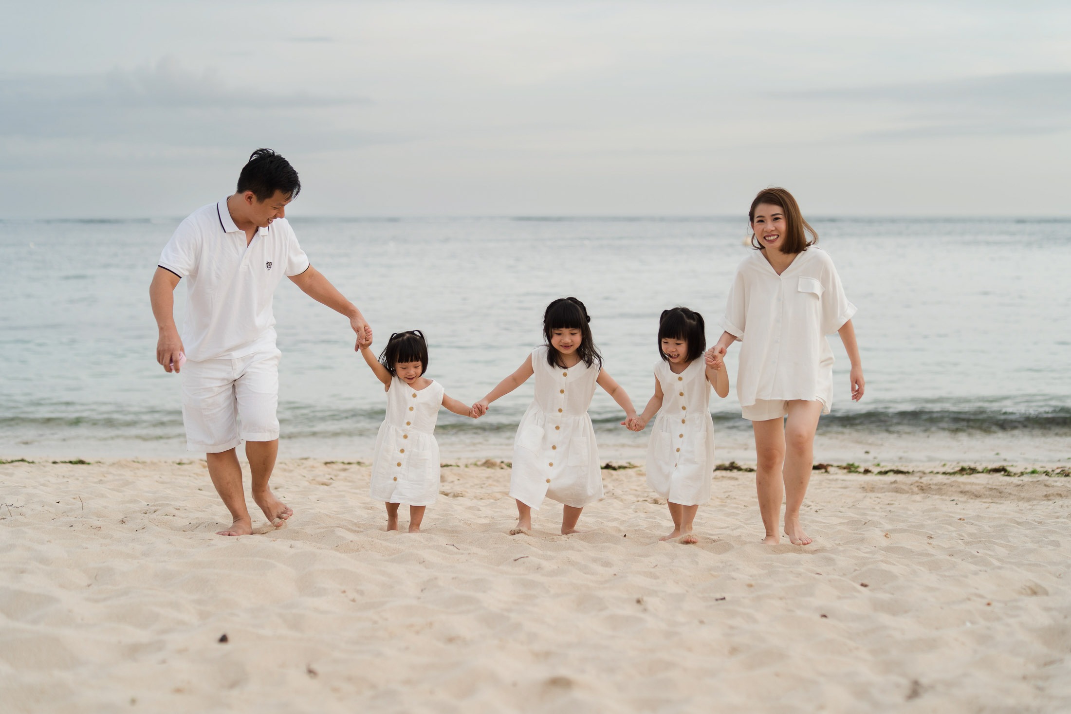 Family walking together along the shoreline at The Mulia Nusa Dua Bali during a sunset family photography session