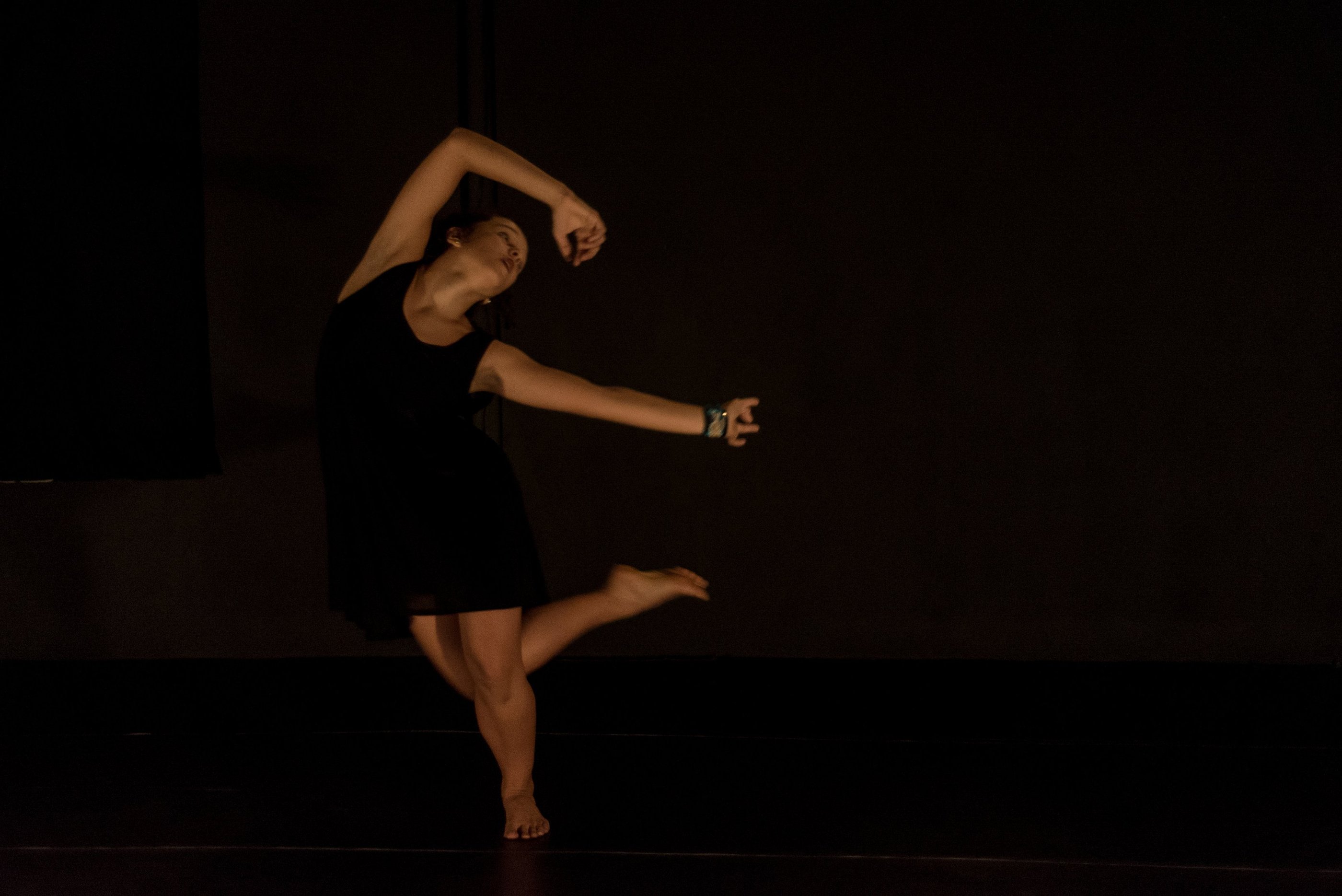 a woman in a black dress is dancing on stage