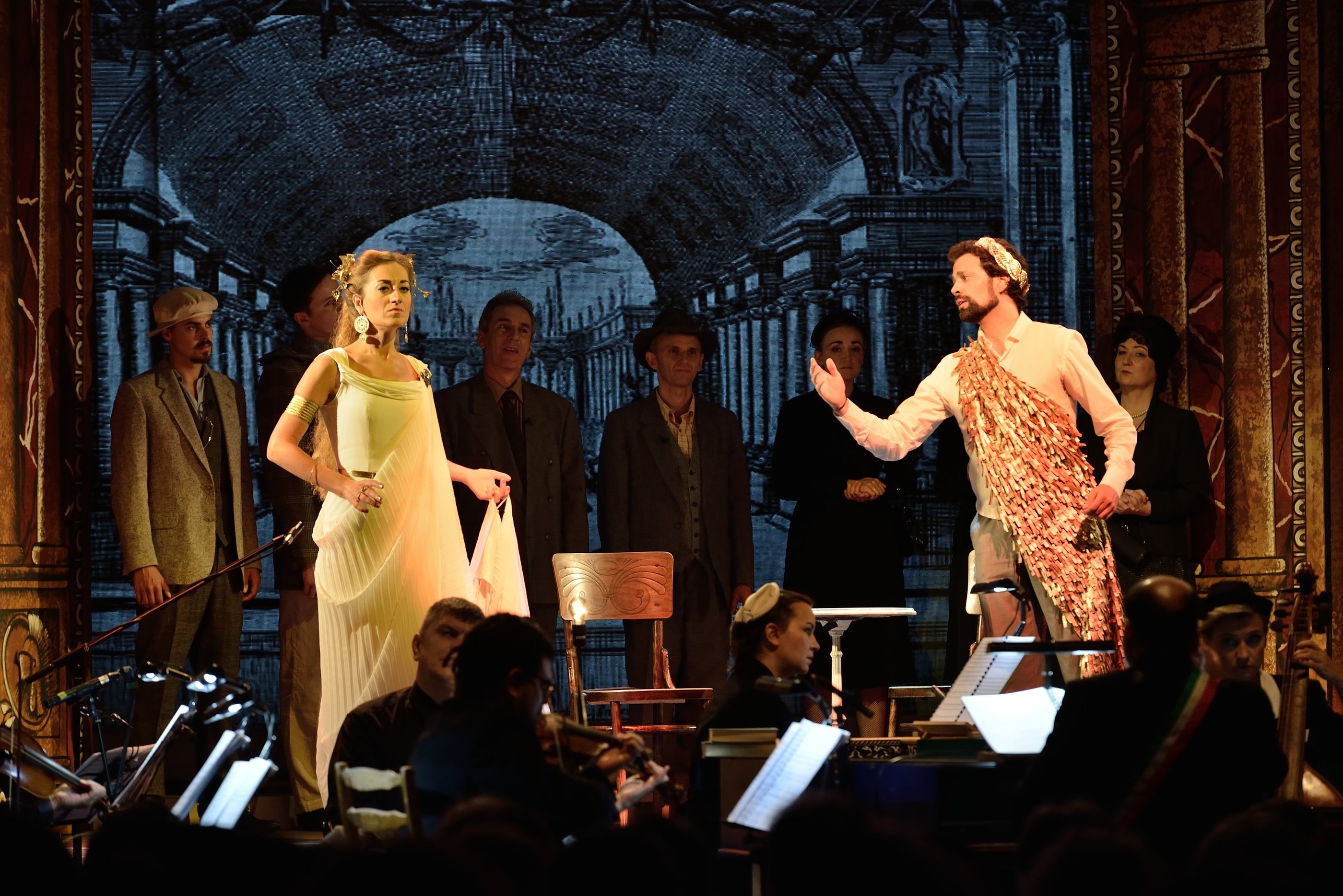 Actors in classical and modern costumes performing on stage during a theatrical opera production.