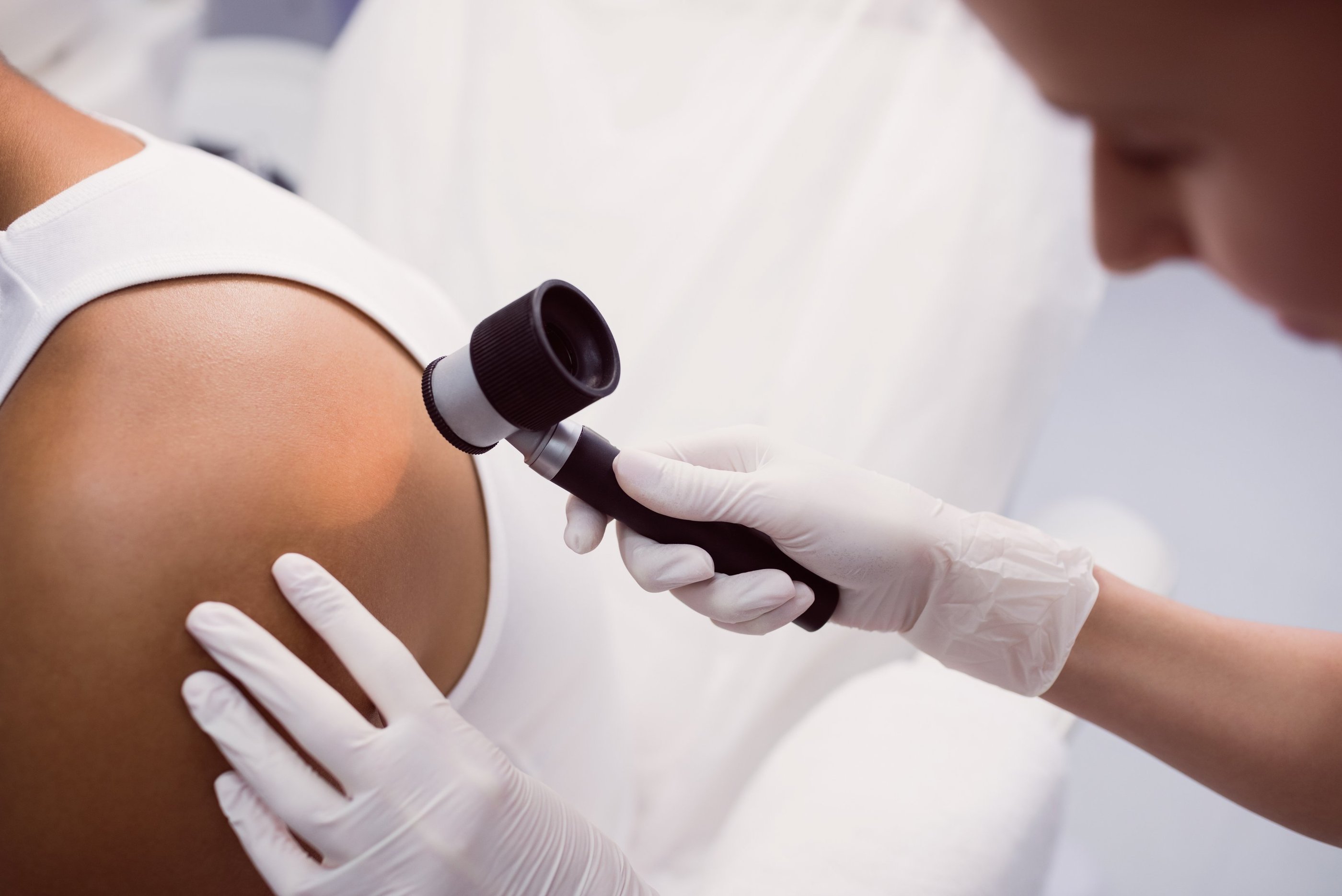 Médico dermatologista realizando dermatoscopia em paciente.