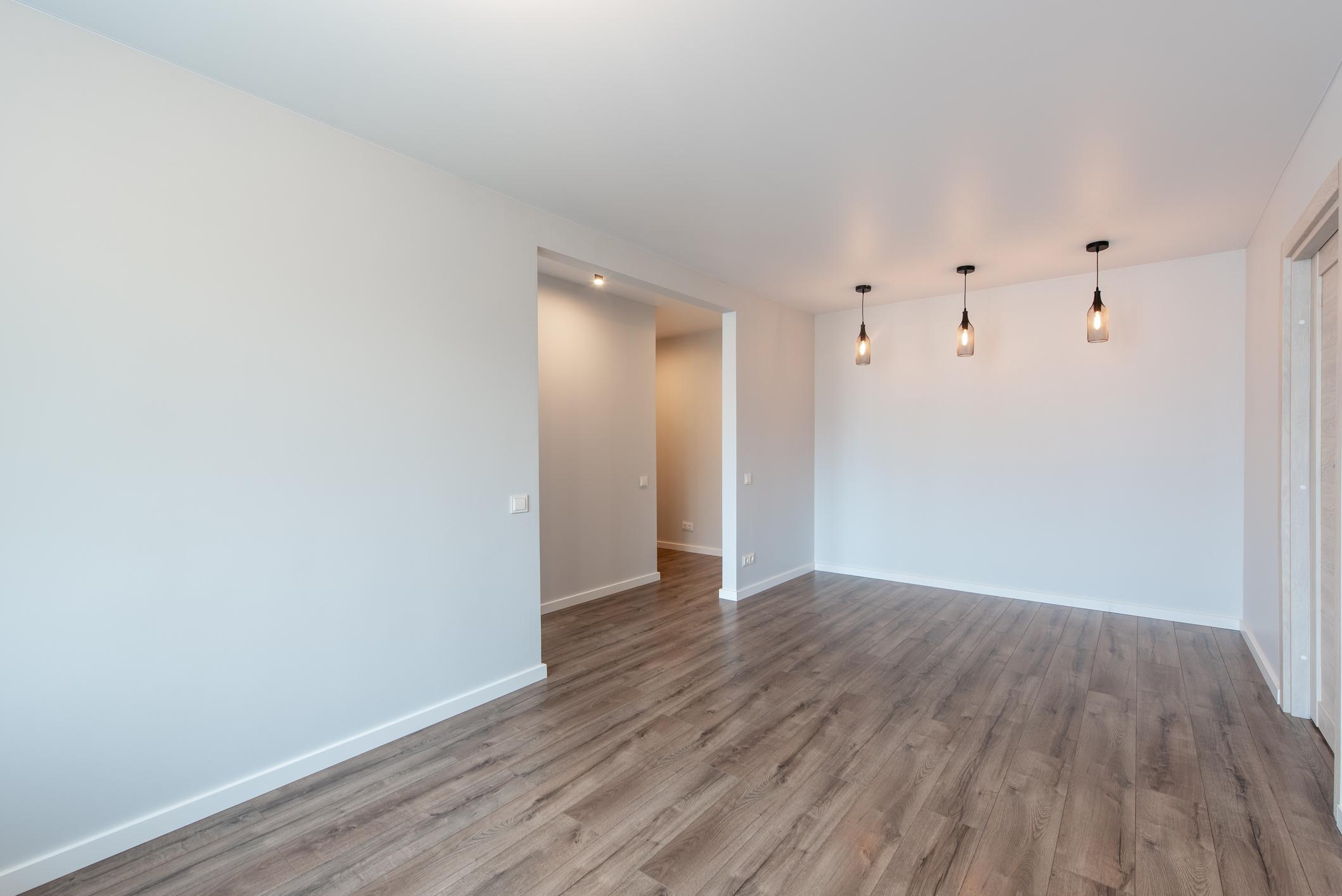 Modern room with hardwood flooring and white baseboards.