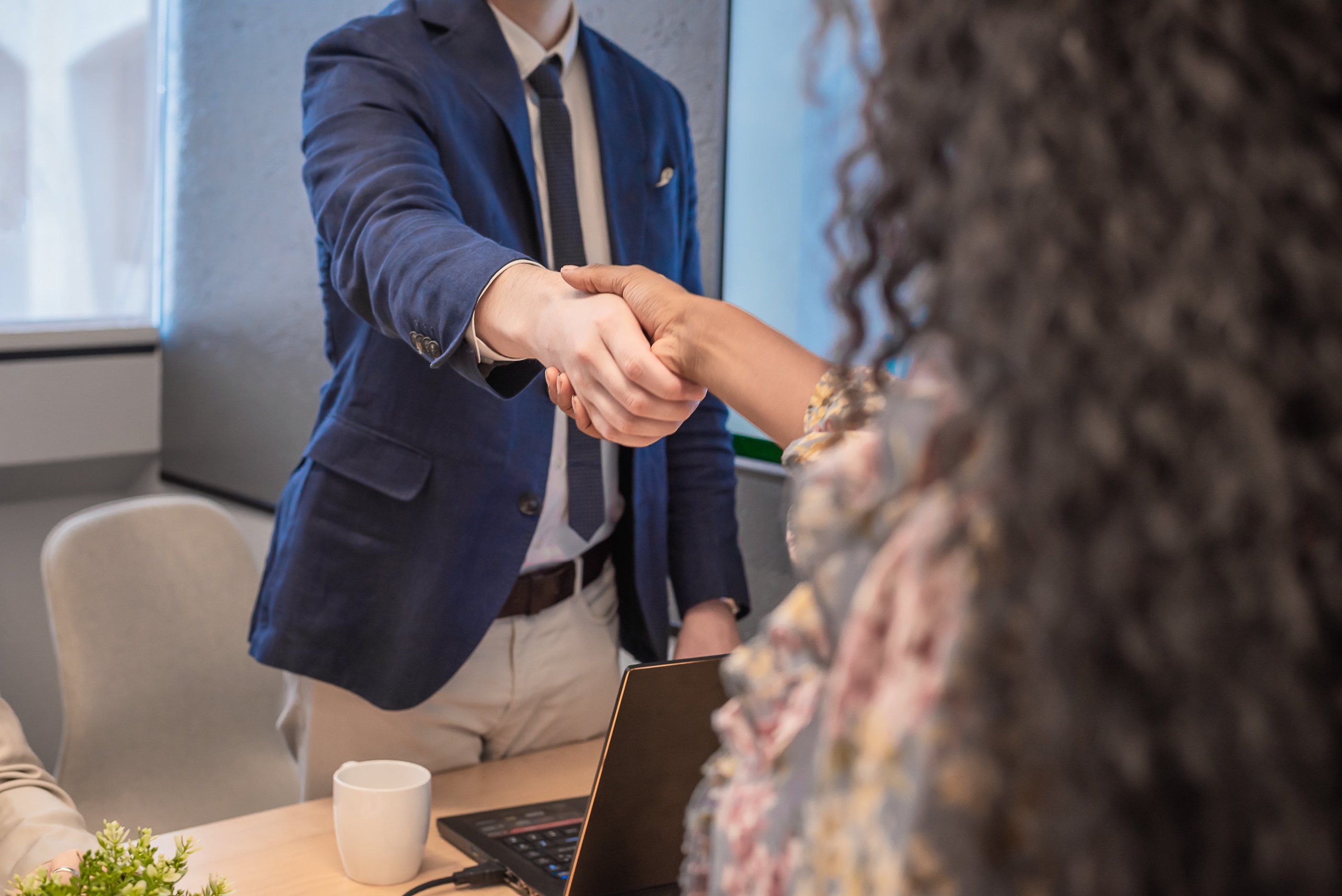 Two people shaking hands in a professional setting.