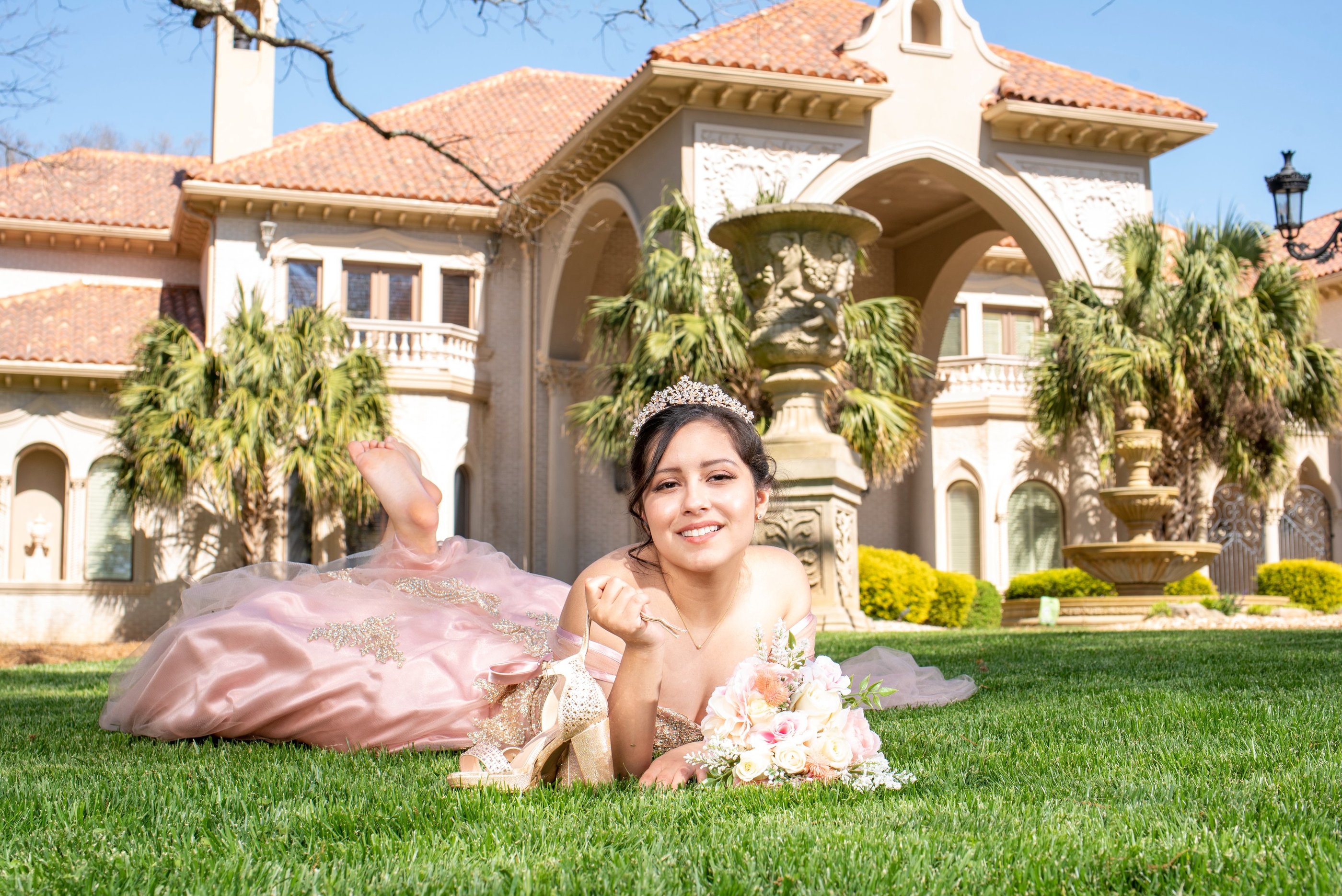 quinceanera princess in a pink dress laying on the grass