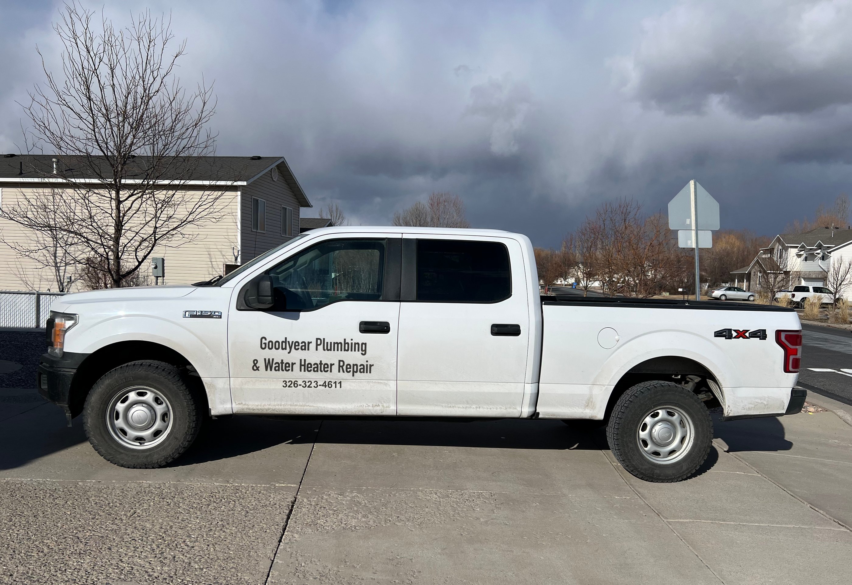 White Goodyear Plumbing & Water Heater Repair service truck parked on a residential street.