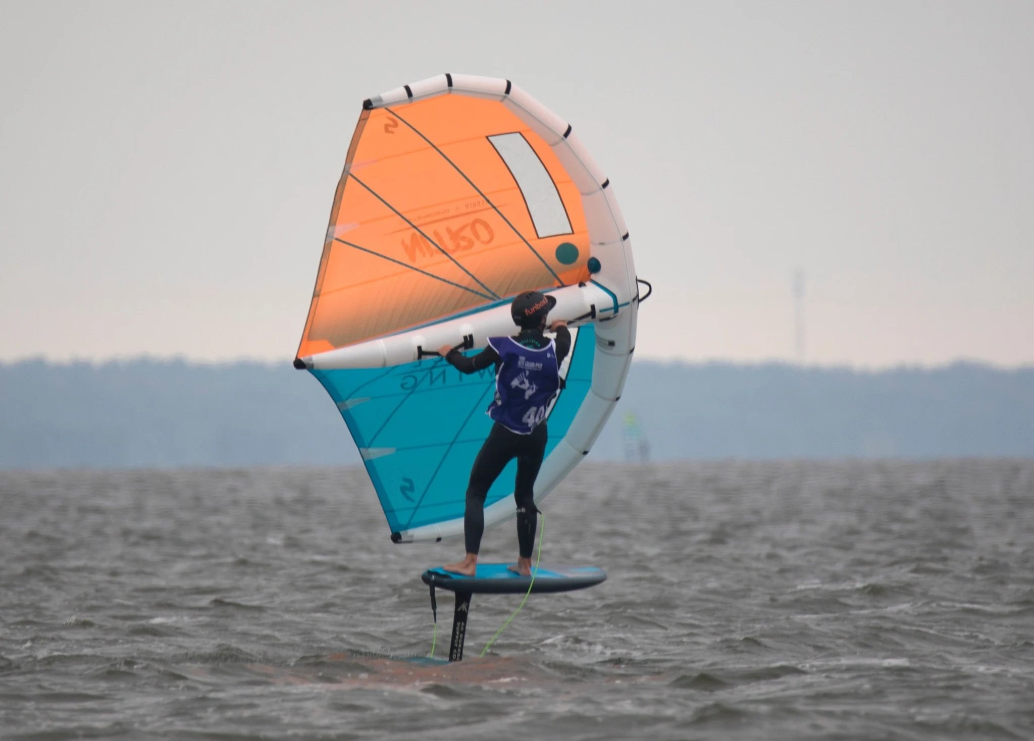 Mokytojas rodo pagrindinius wing foil valdymo principus ant kranto