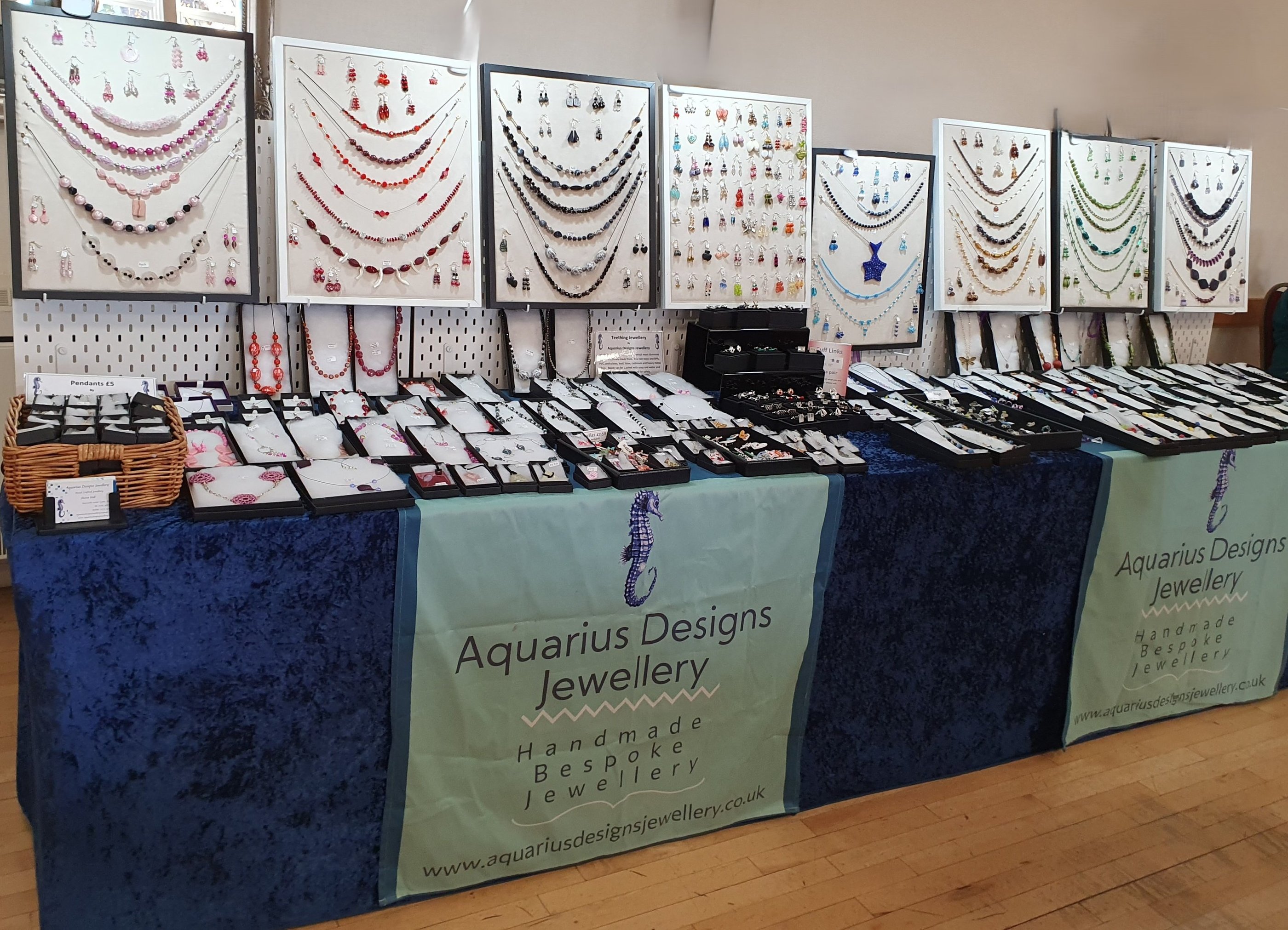 Handmade jewellery display featuring necklaces and earrings at an Aquarius Designs Jewellery stall