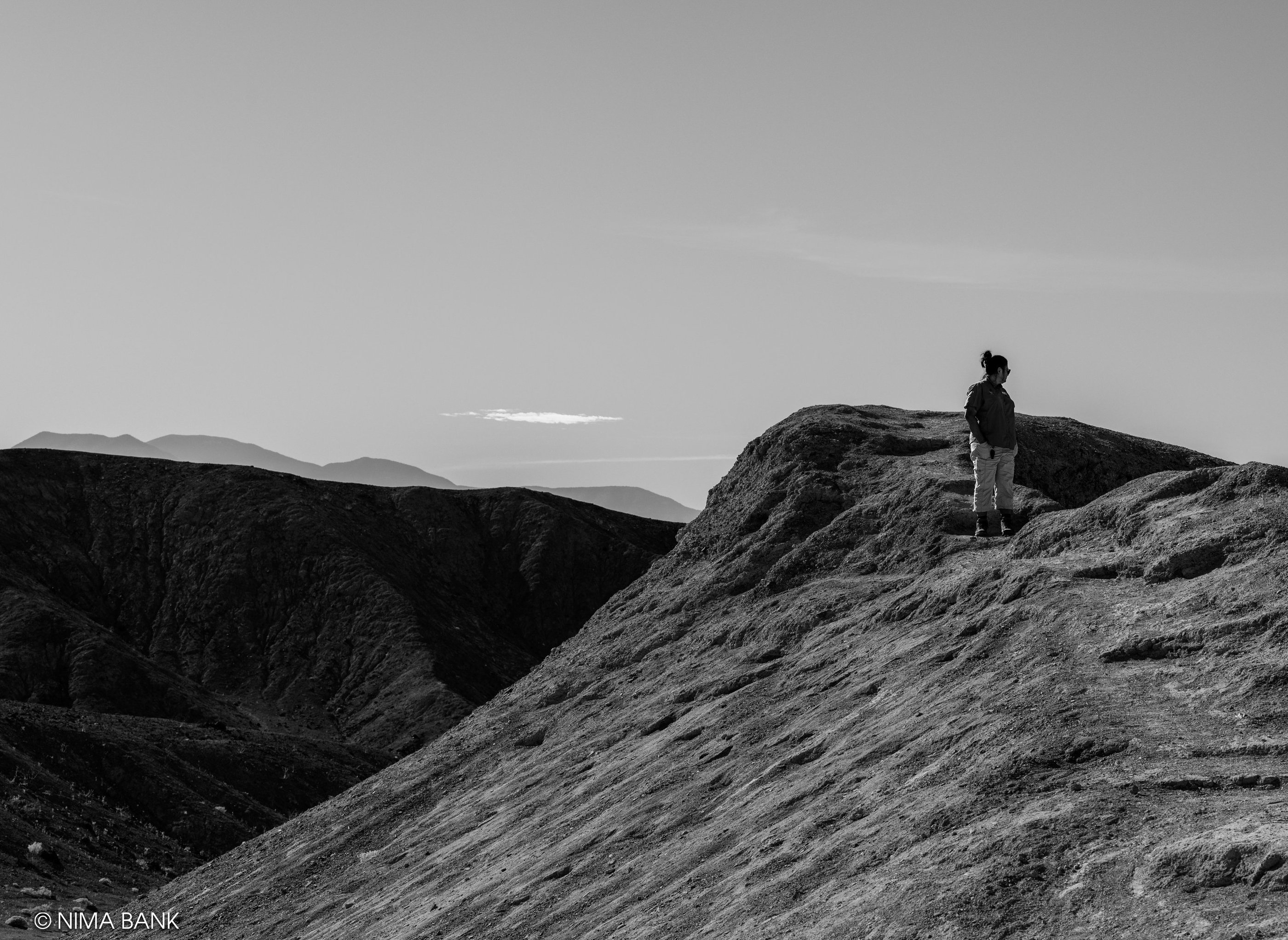 a person standing on a mountain top in black and white in death valley