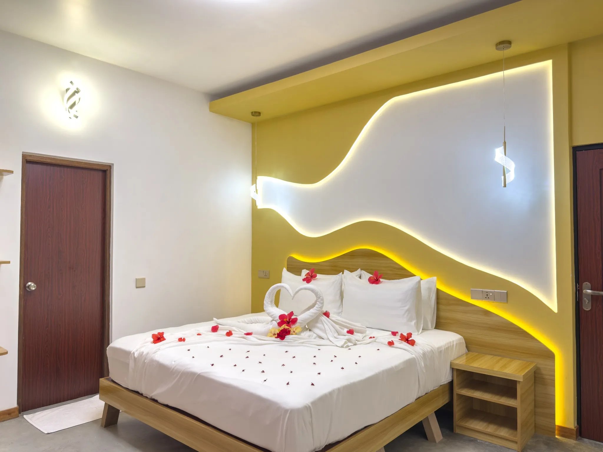 Luxury hotel bedroom with towel swans and rose petals on a bed for a romantic honeymoon suite setup.