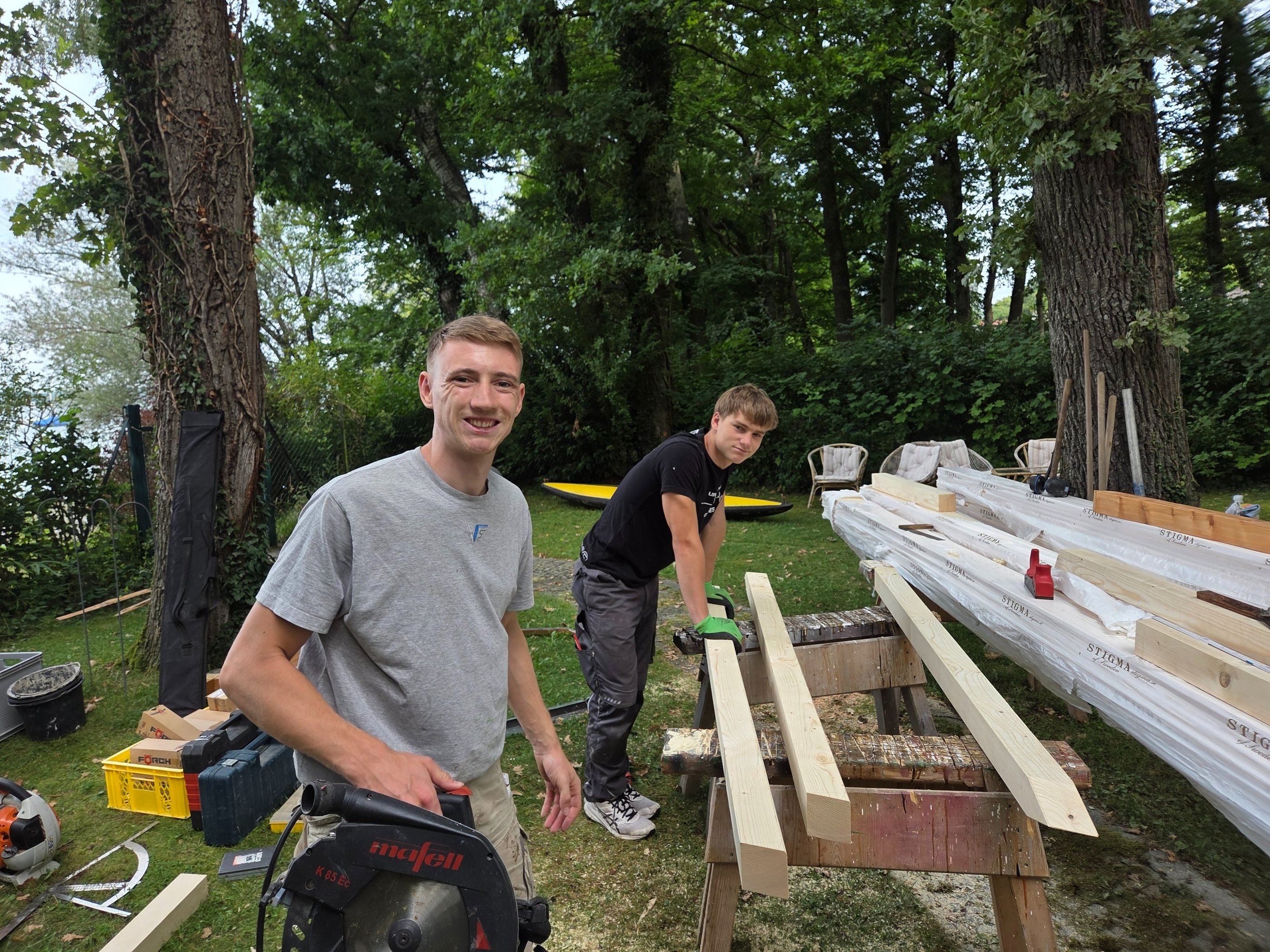 Gut gelaunte Azubis von Holztechnik Volk bei Holzarbeiten im Garten am Ammersee.