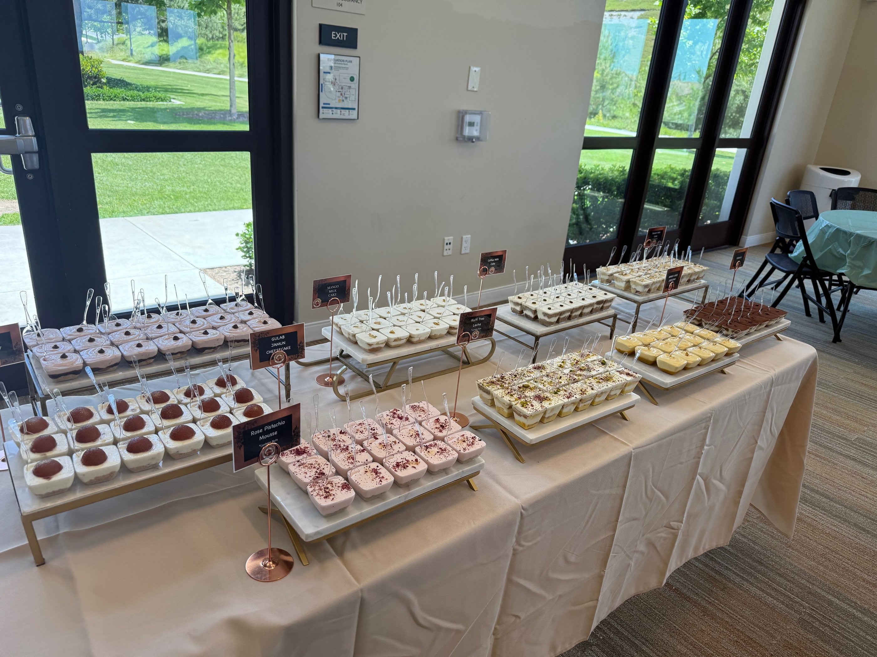 Indian Desert cups for a catering event laid out on a table. With gulab jamun, mousse, etc.