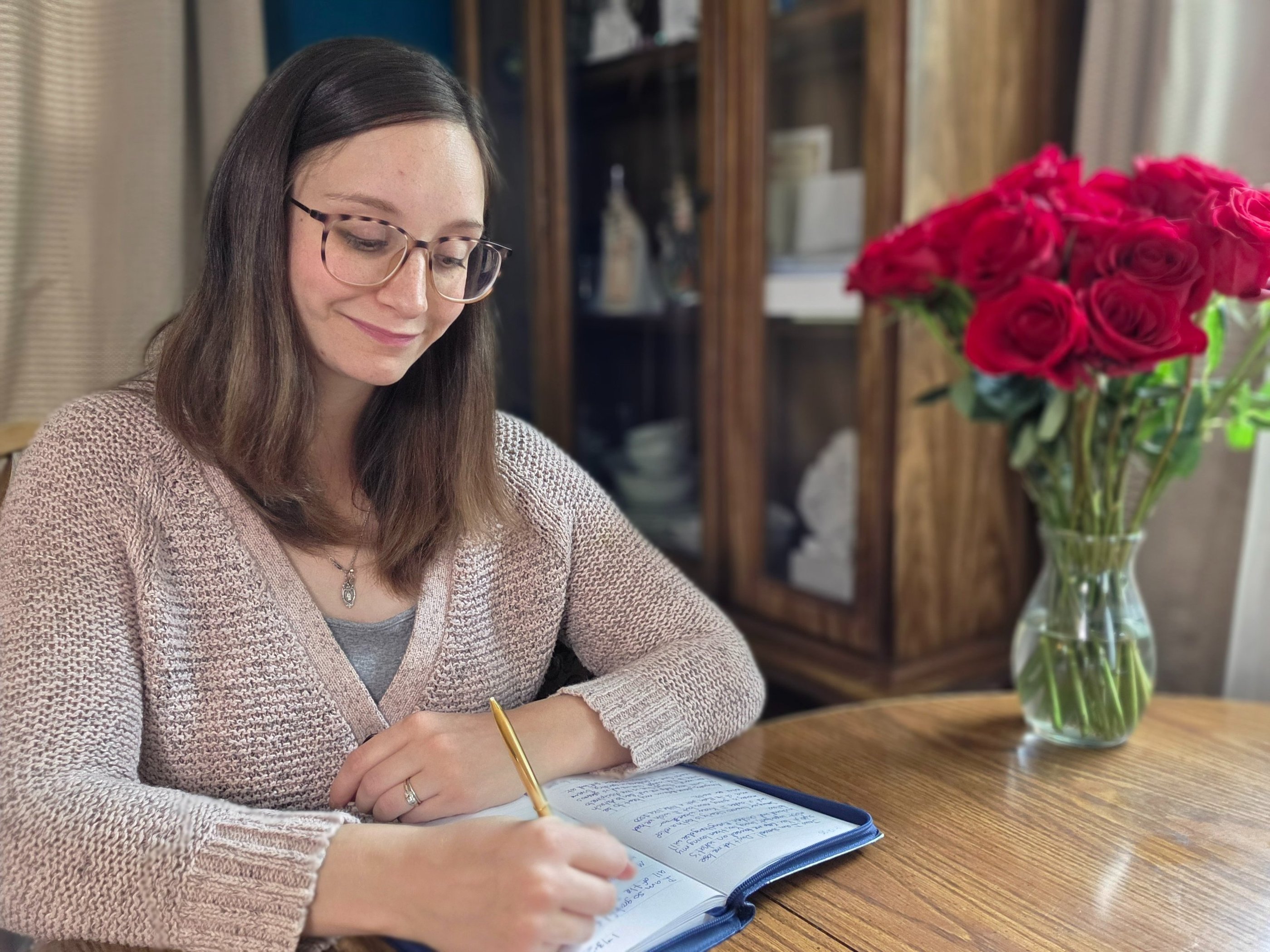 a woman sitting at a table with a pen and notebook