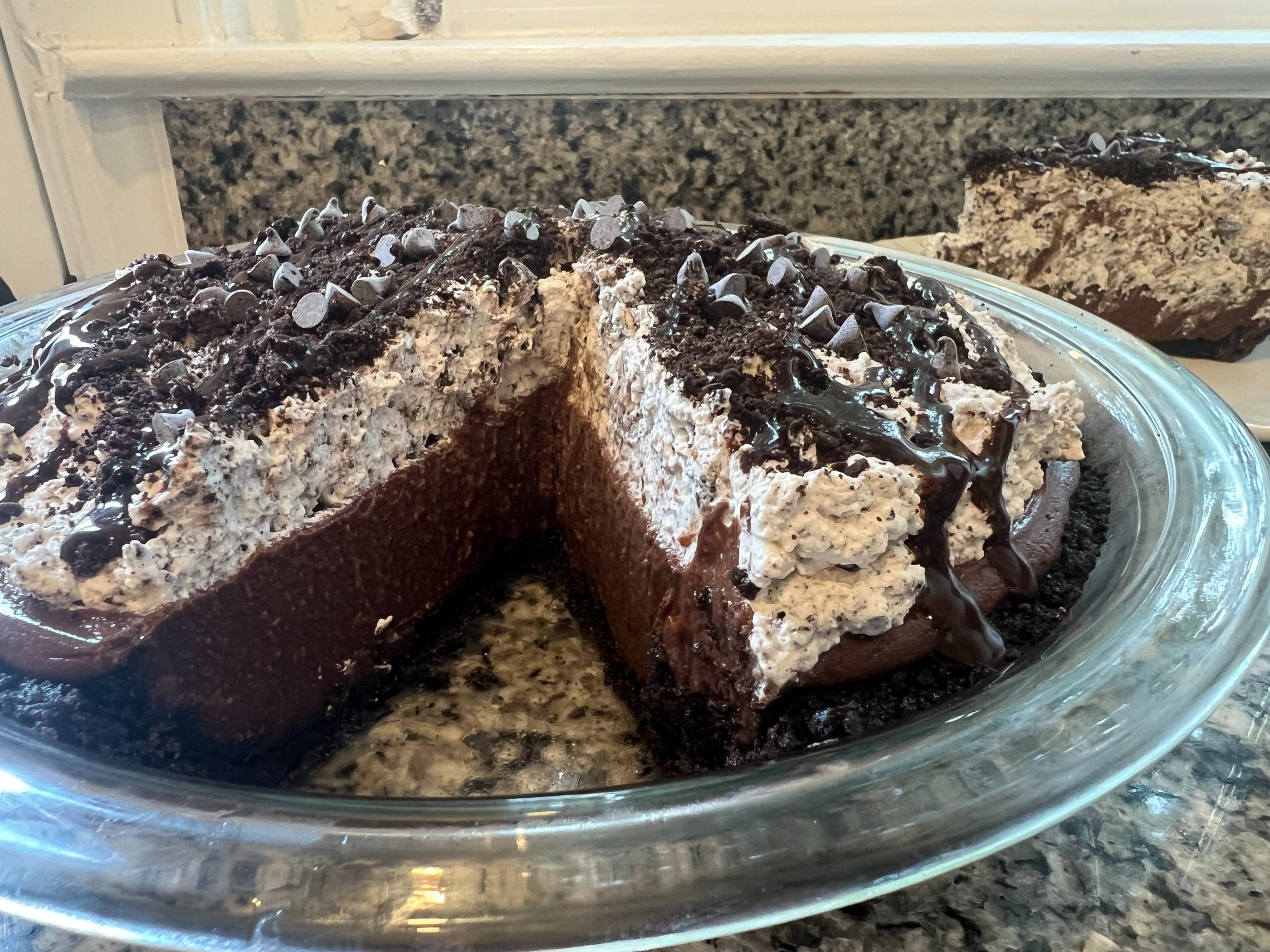 chocolate silk pie with cookies and cream whipped topping and chocolate chips in a glass dish.