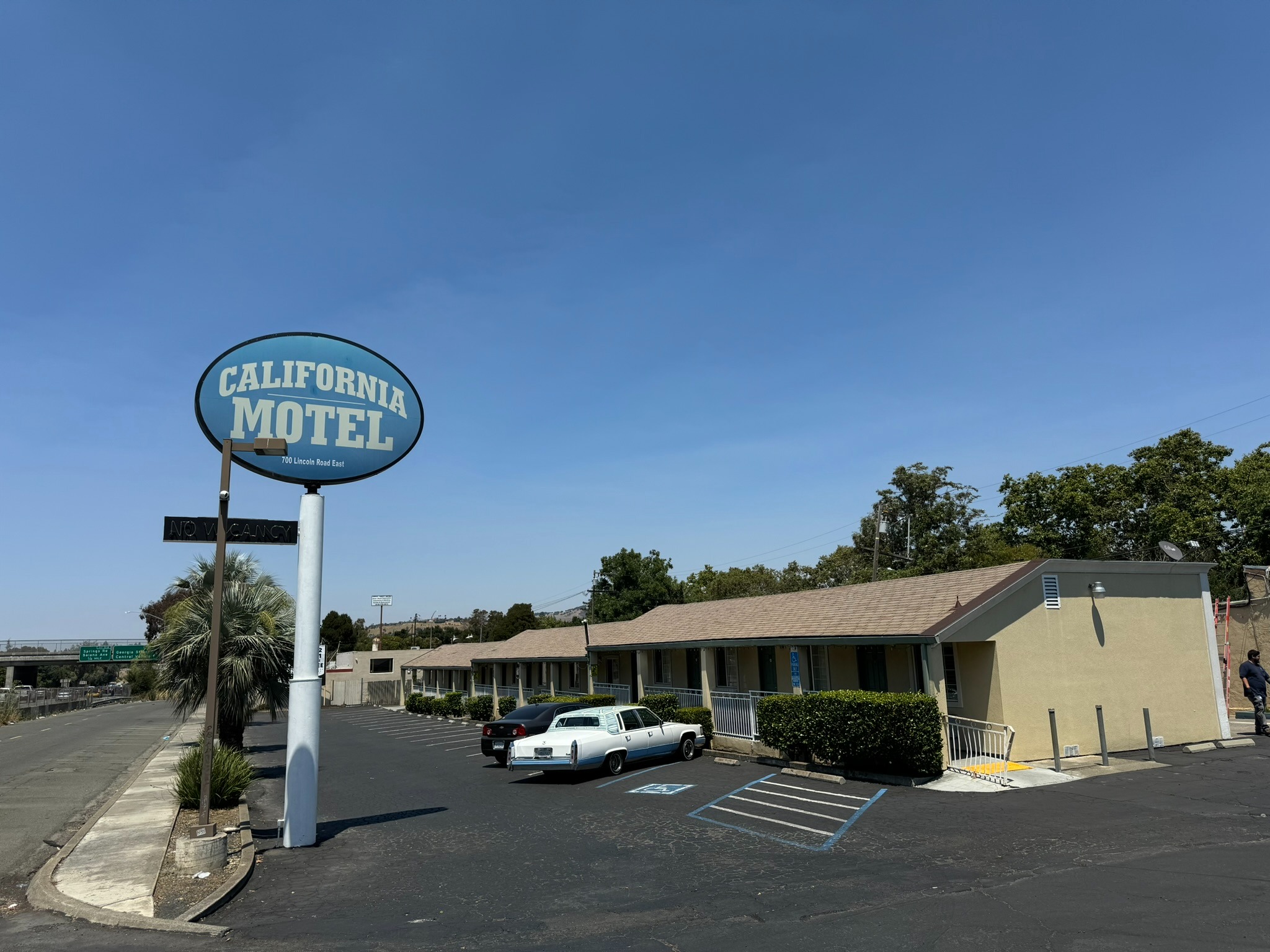 a motel sign that says california motel with the motel in the background and a blue sky