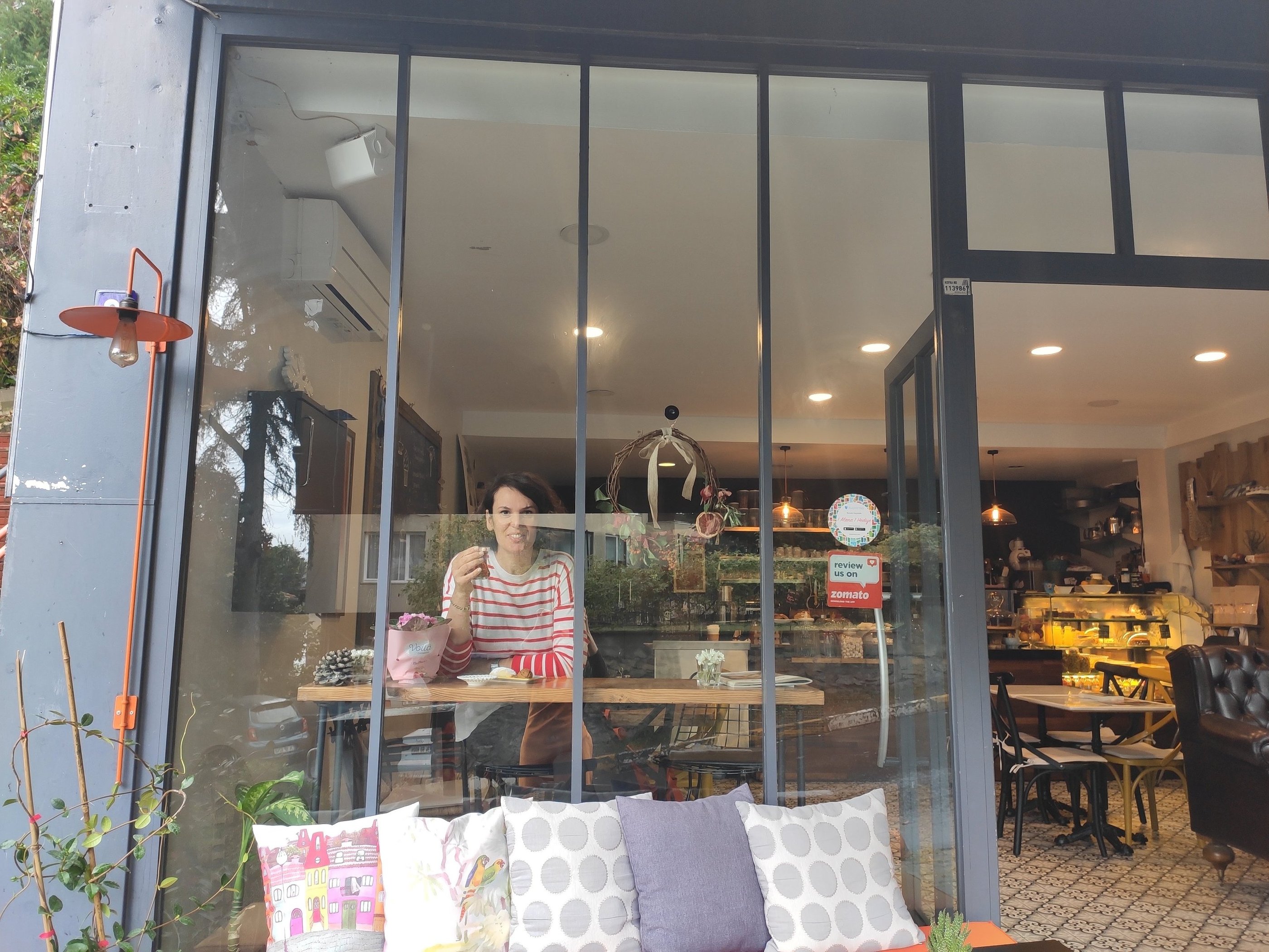 Cozy interior of Cafe Boyacıköy with pastel green and blue tones, showcasing fresh bread and pasta on display.