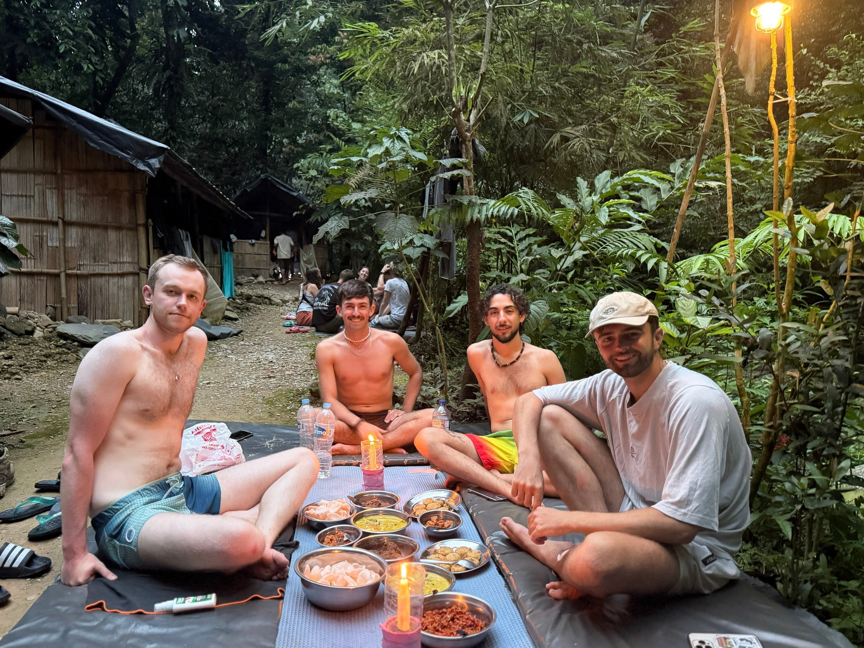 Friends enjoying a traditional dinner by candlelight at a jungle retreat base camp.