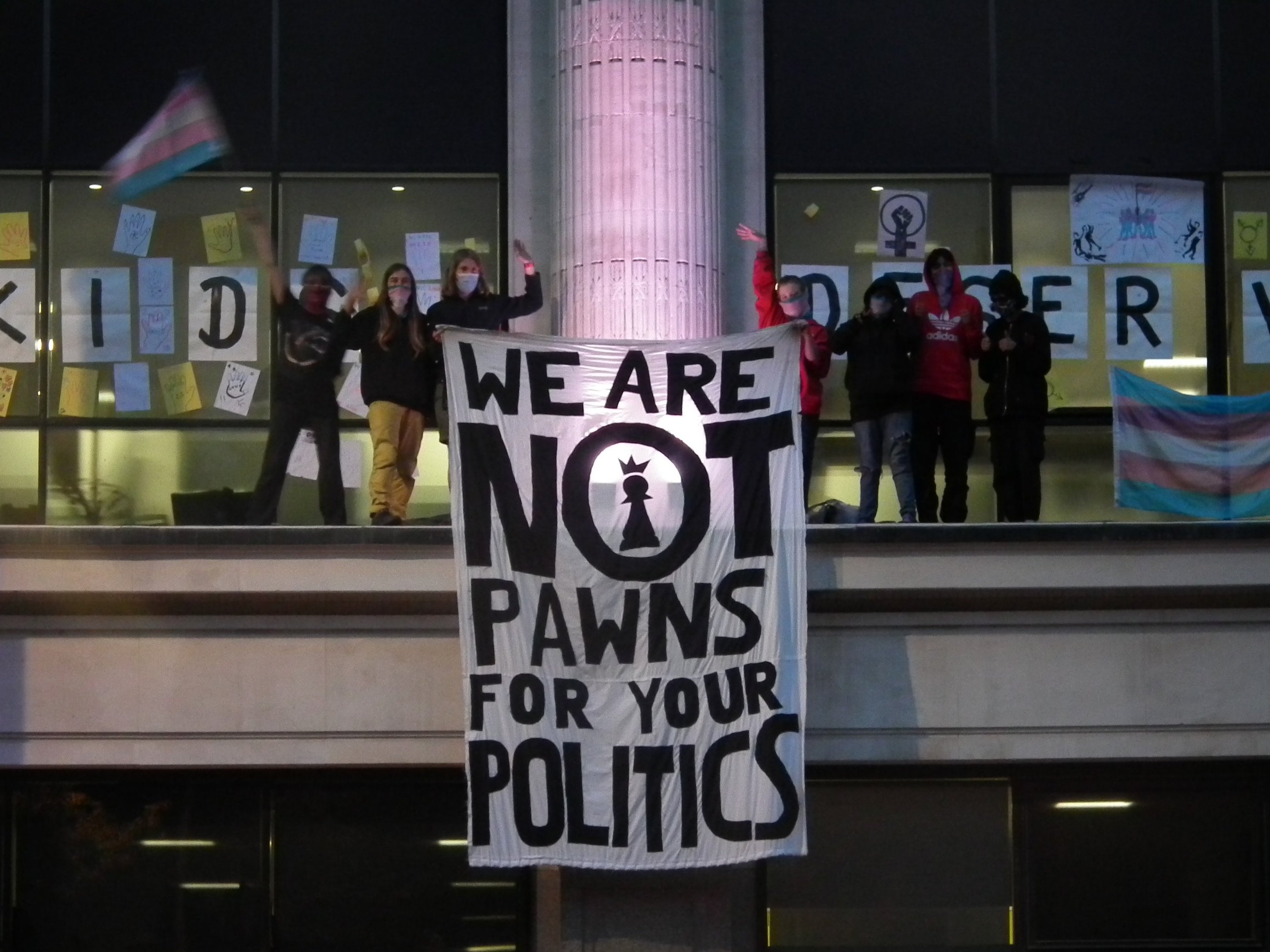 Activists standing on top of NHS England offices with a banner "we are not prawns for your politics"