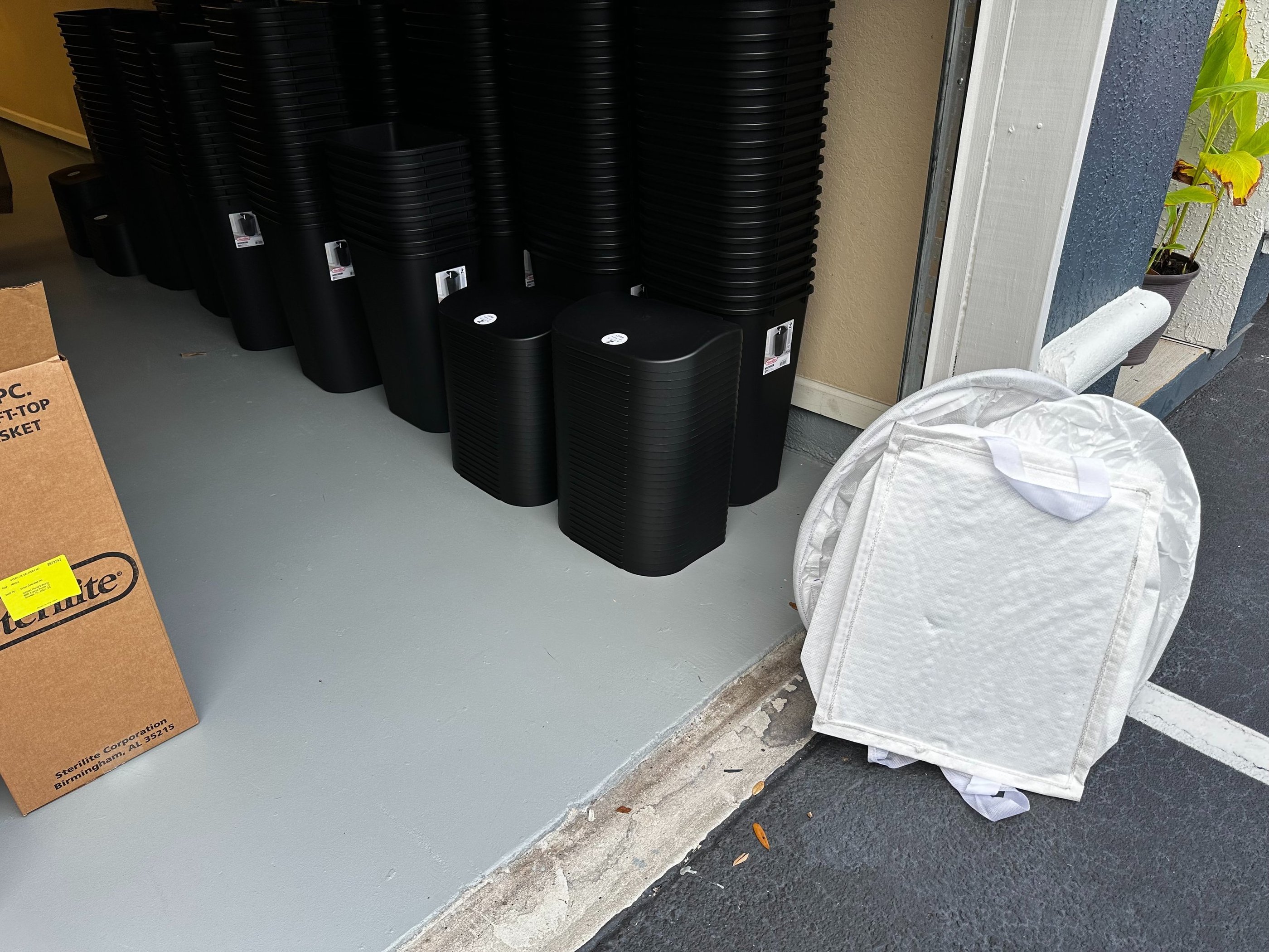 black trash cans stacked in a garage
