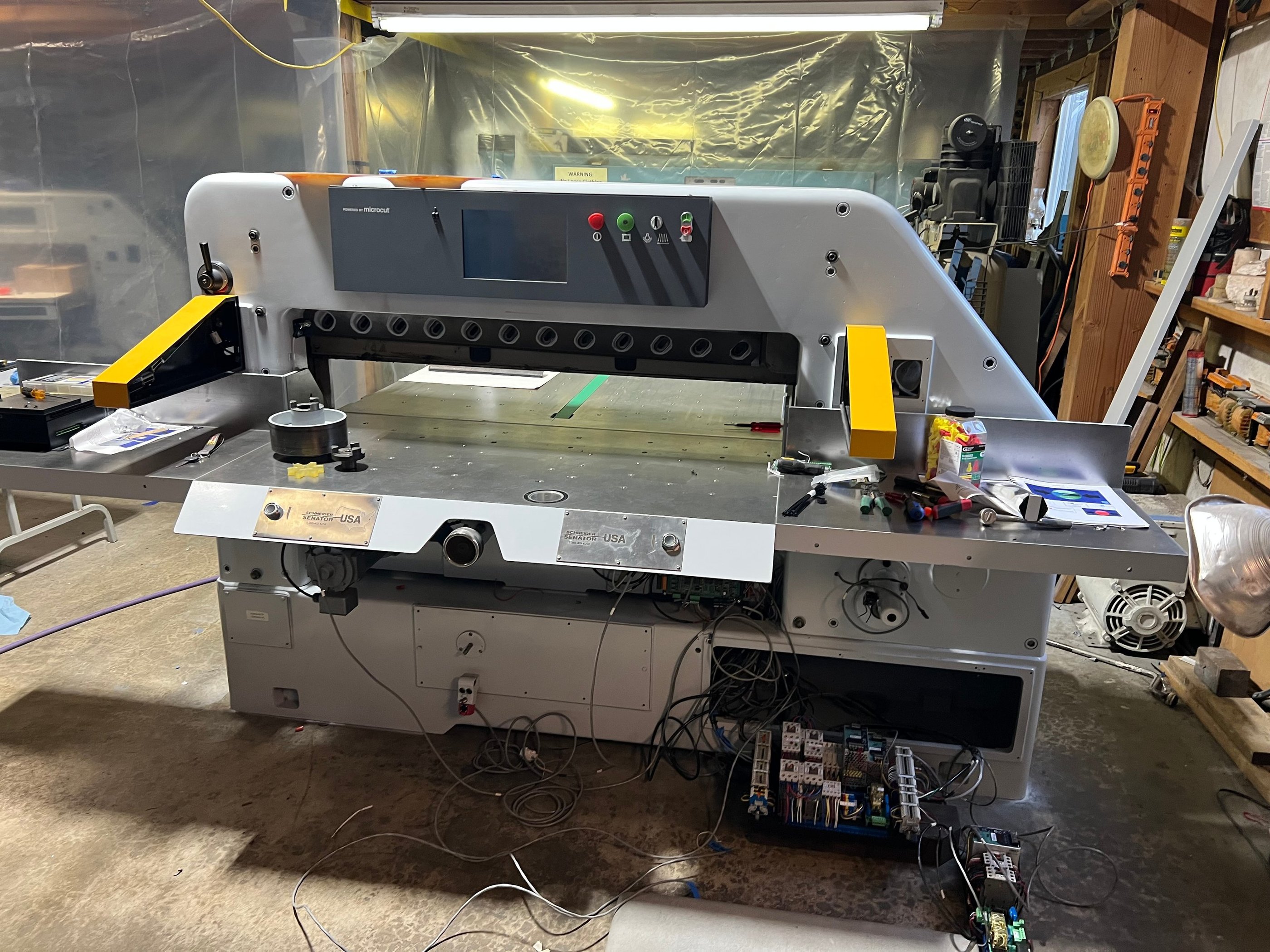 Two stainless steel laser engraved cut button covers installed on a guillotine paper cutter