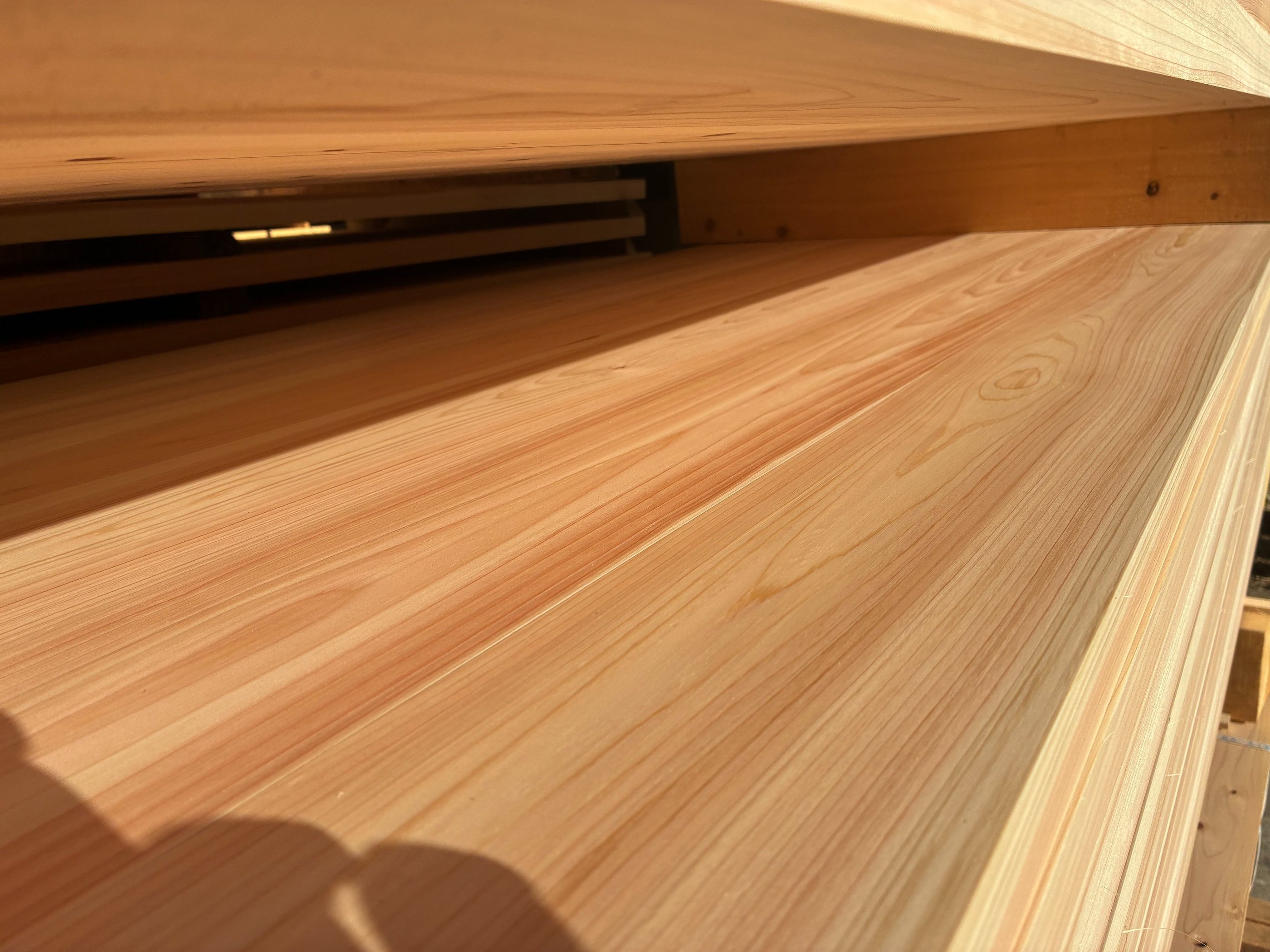 Close-up of smooth, light-colored cypress wood planks stacked at a lumber yard.