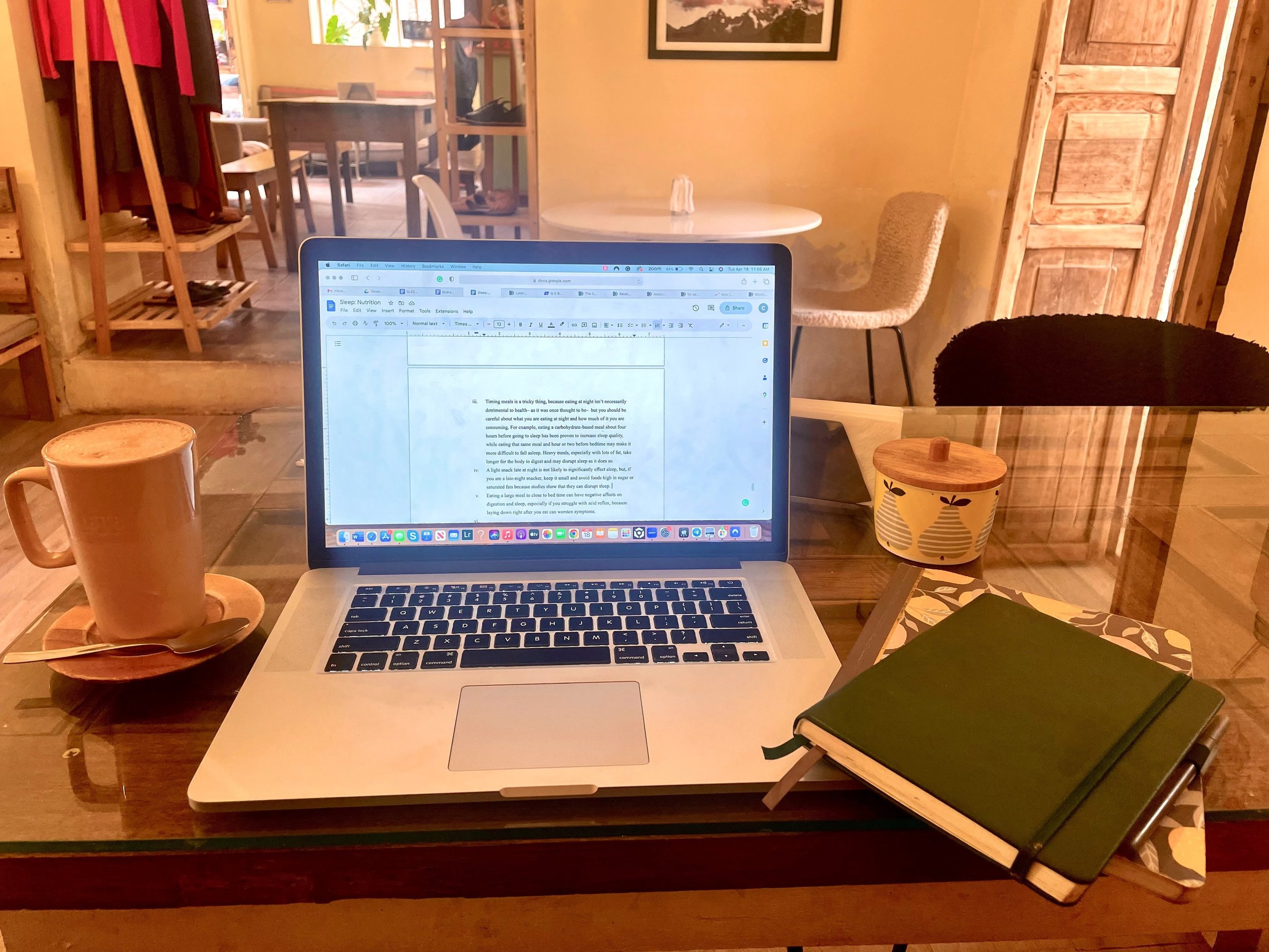 A laptop on a cafe table next to a latte and notebook, perfect for remote work or blogging.