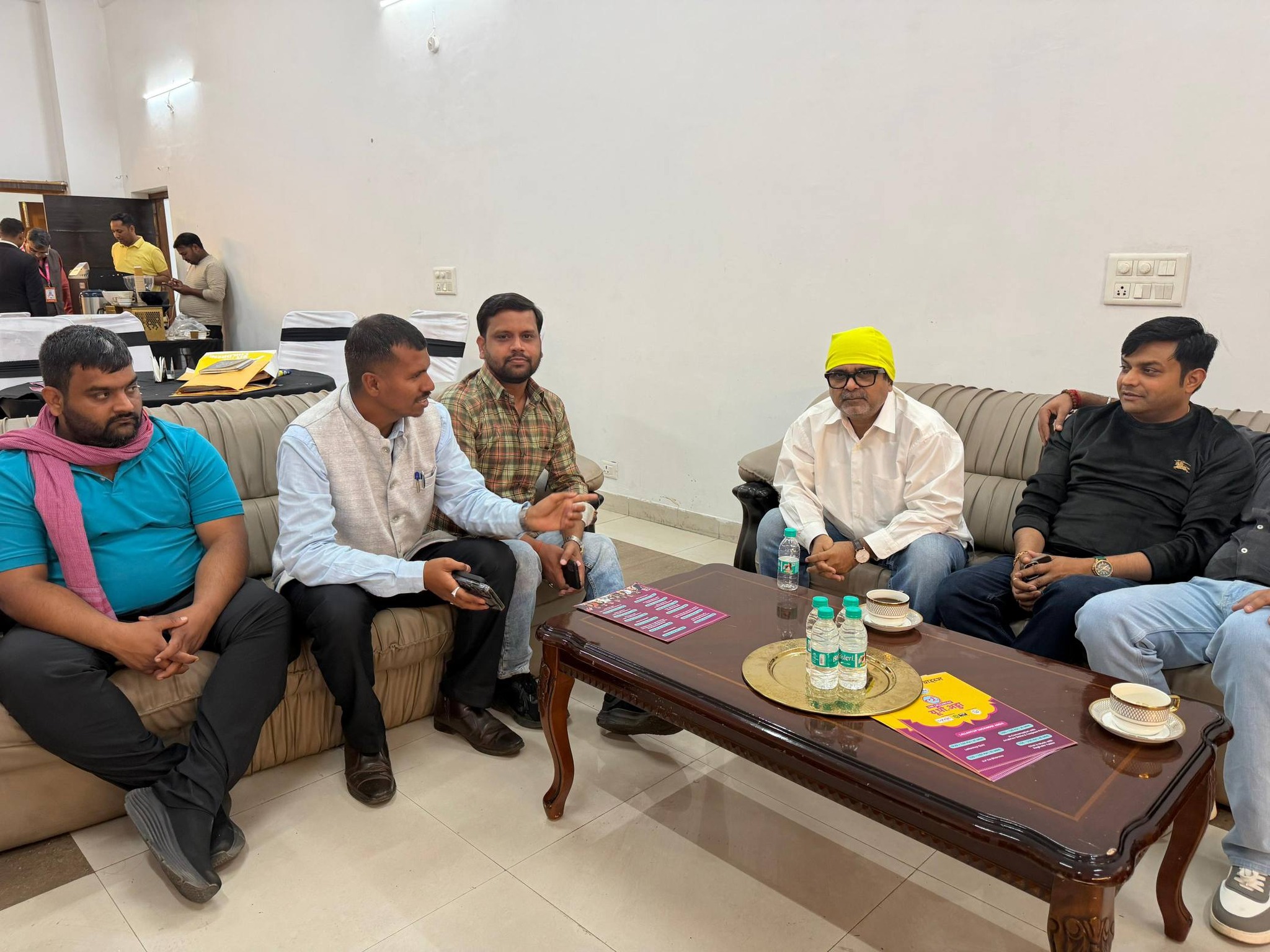 A group of men having a formal discussion while sitting on sofas around a wooden coffee table.