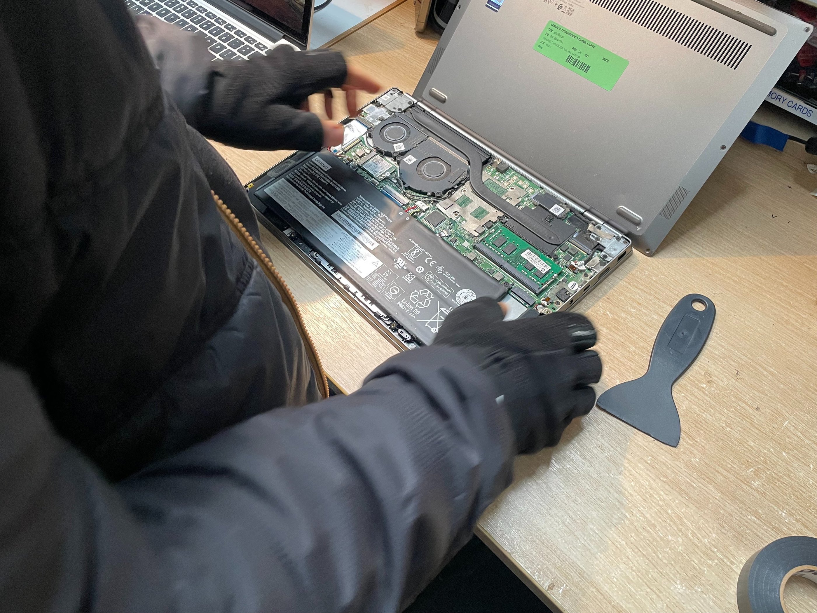 A technician repairing an open laptop computer on a wooden workspace.
