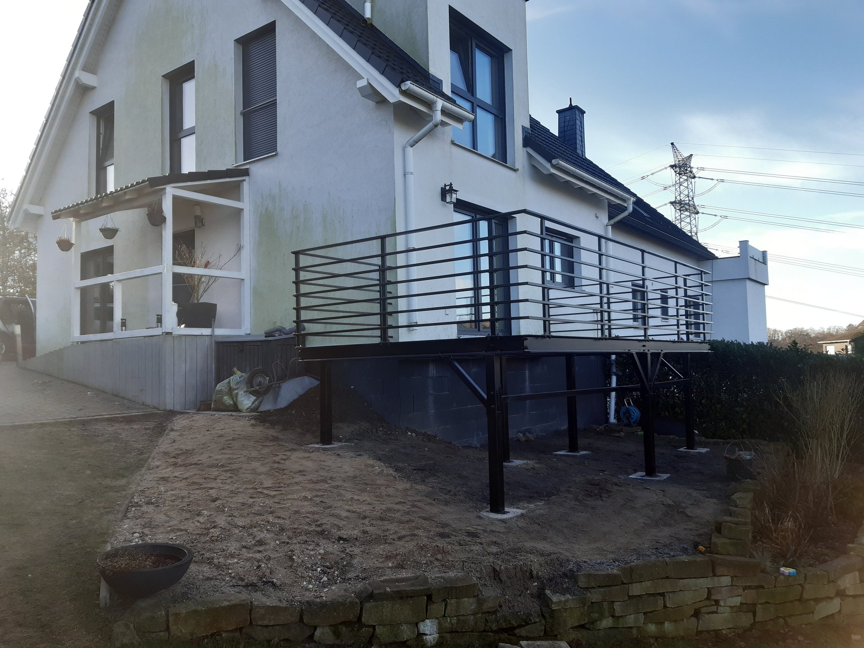 Modern black metal balcony railing installed on a raised outdoor metal deck.