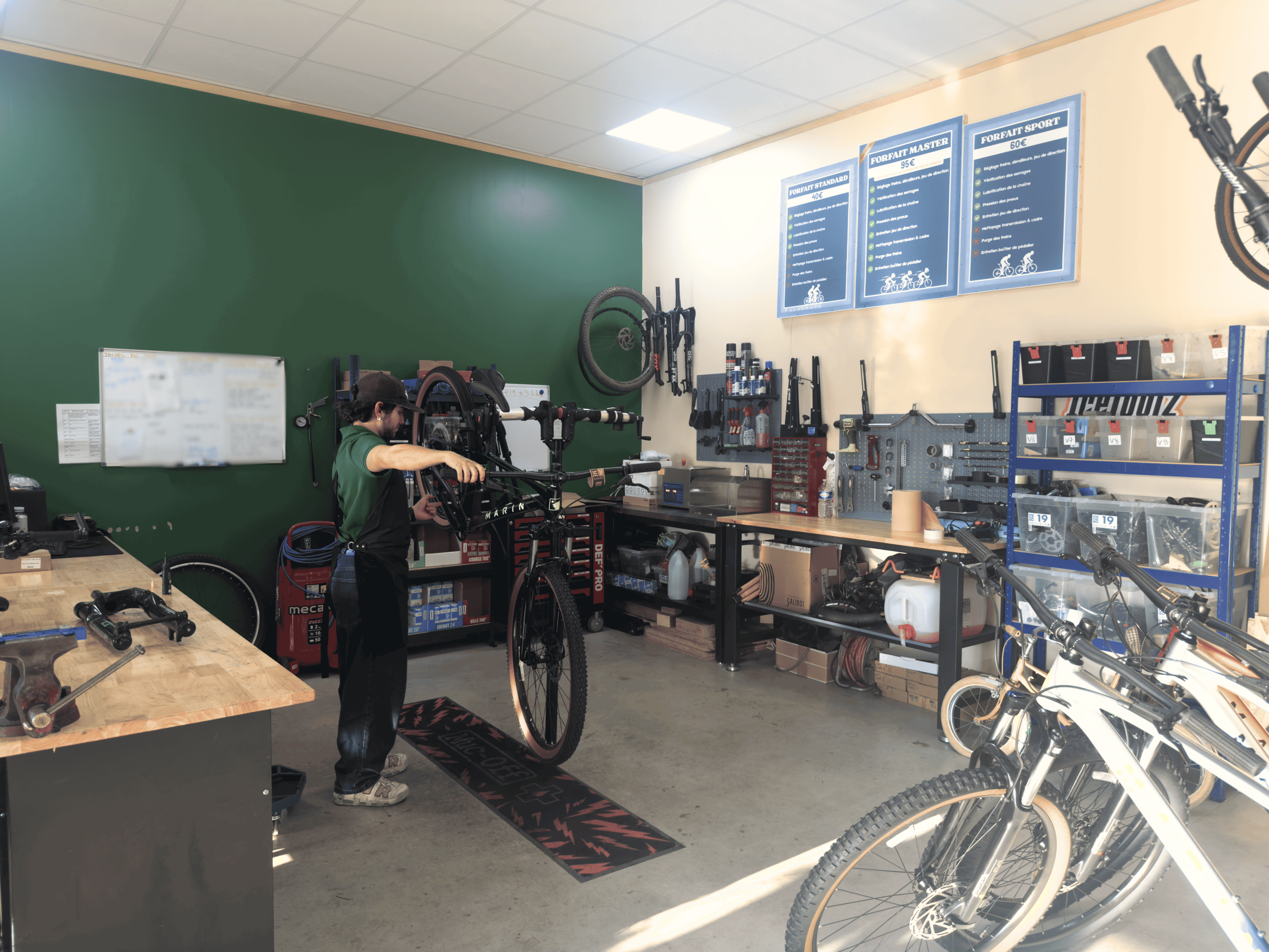Professional bicycle mechanic repairing a mountain bike on a stand in a fully equipped bike workshop.