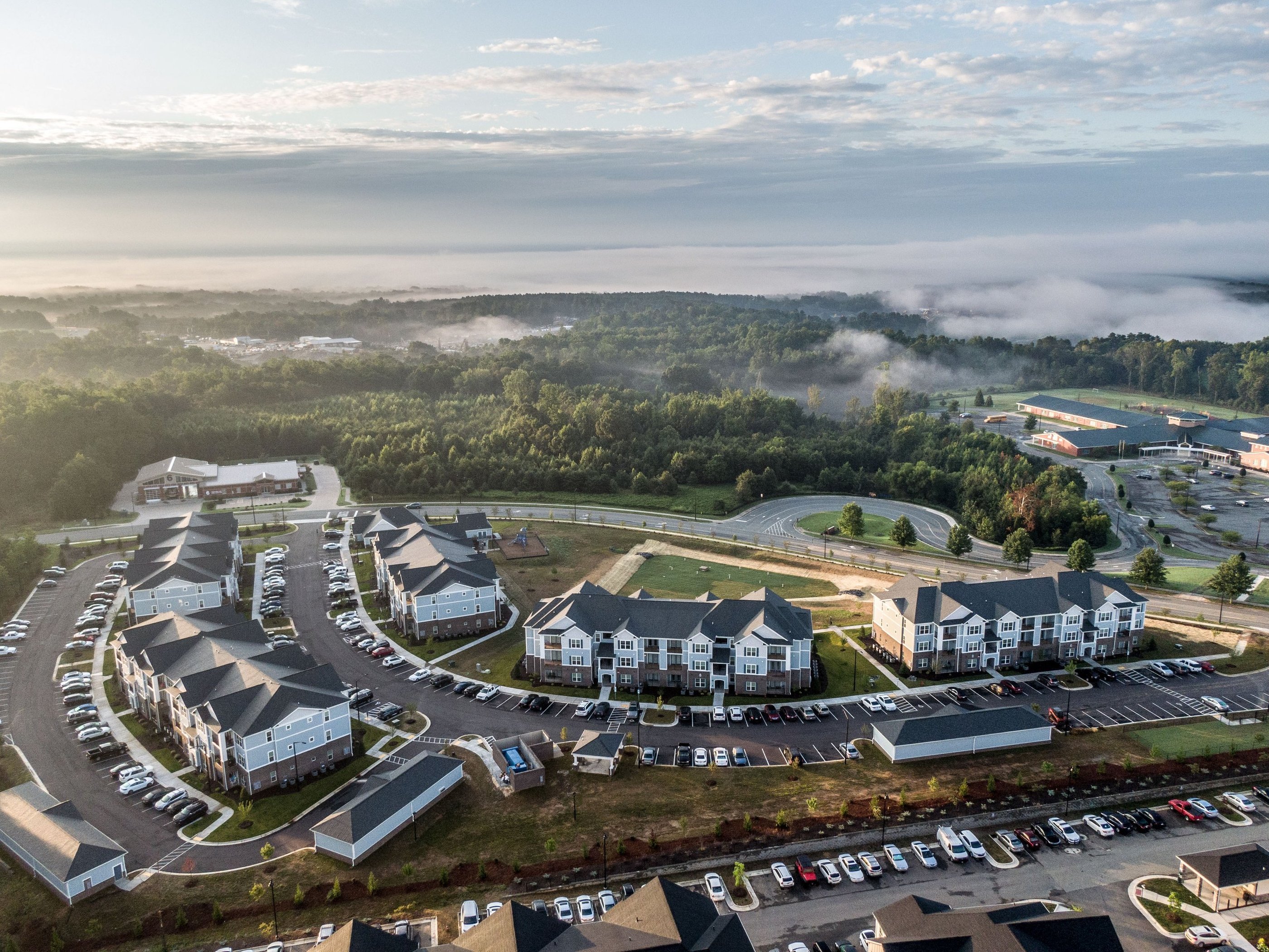 Aerial view of a completed multifamily apartment community with residential buildings, parking areas, and green space.