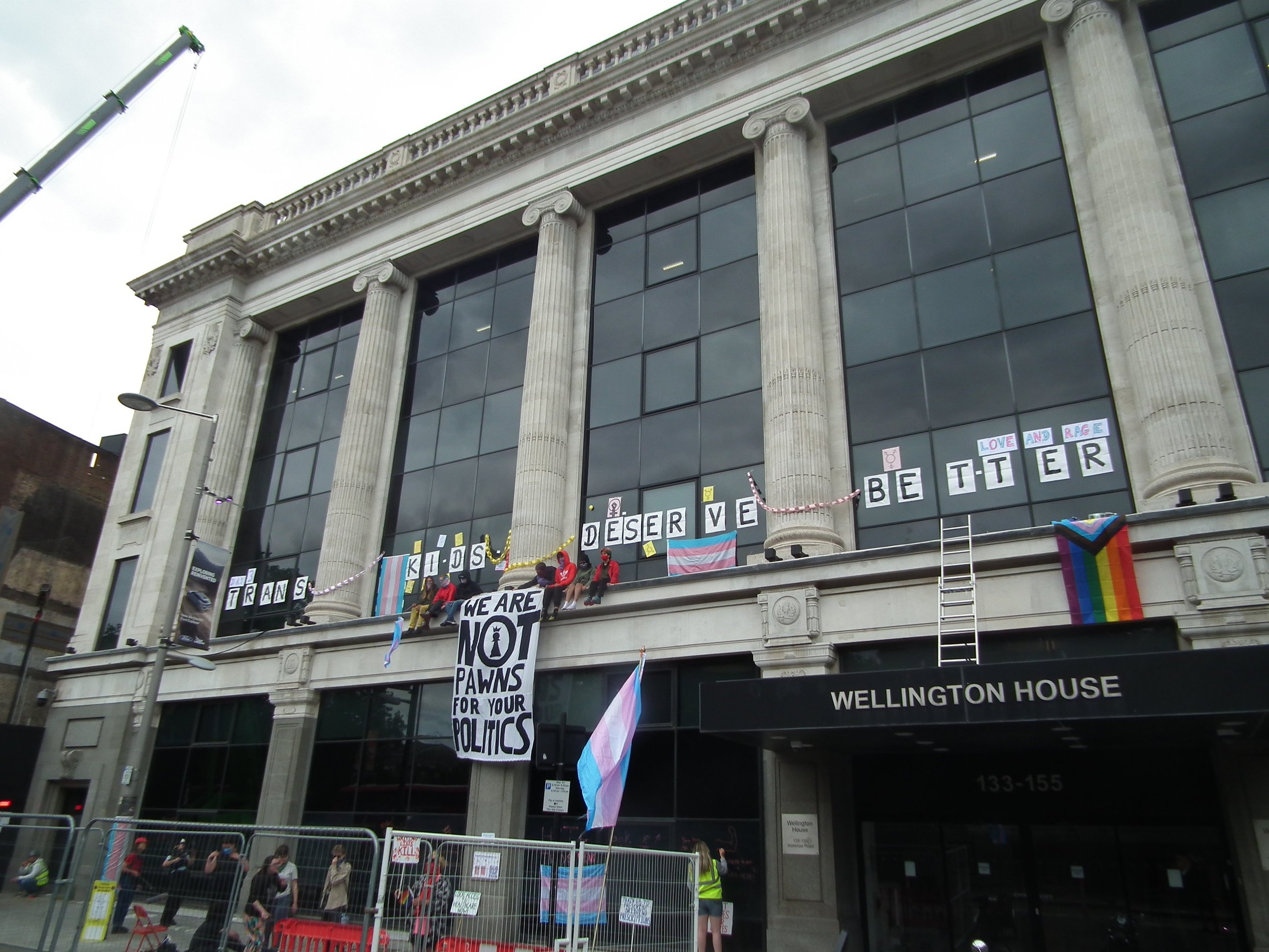 Activists sitting on top of NHS England offices with a banner "we are not prawns for your politics"